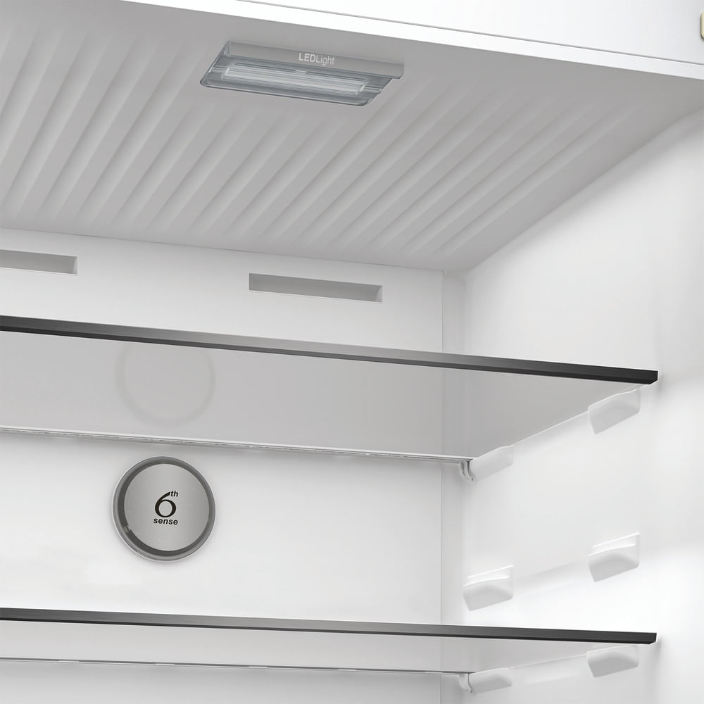 Interno di un frigorifero bianco con ripiani in vetro. Luce LED in alto. Logo '6th sense' sul lato.
