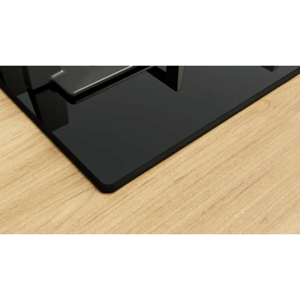 Czarna płyta grzewcza z błyszczącą powierzchnią na drewnianym blacie. Płyta ma prostokątny kształt i gładkie wykończenie.