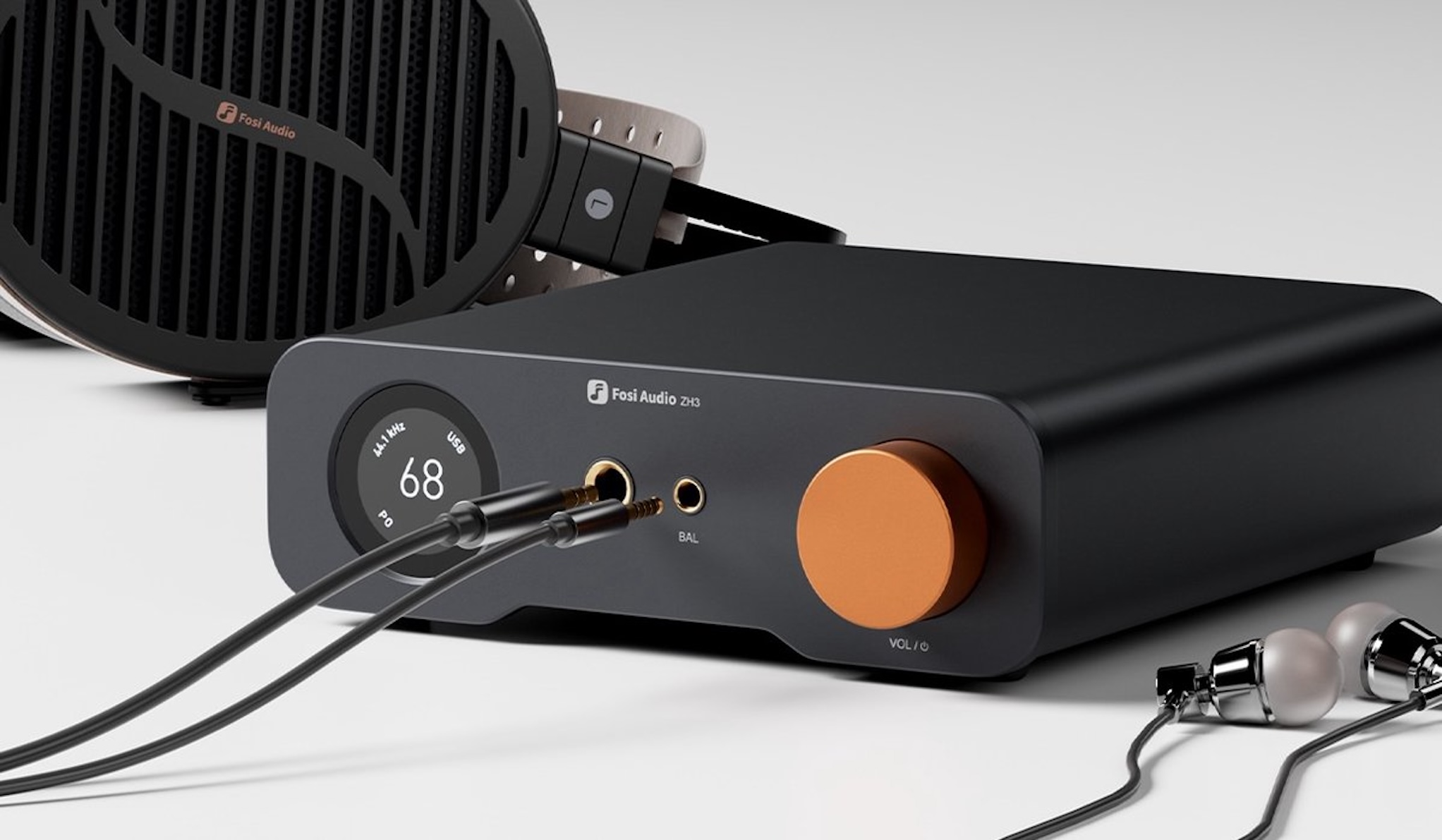 Un amplificador de audio negro con una perilla naranja, auriculares y audífonos. Los cables están enchufados. El fondo es blanco.