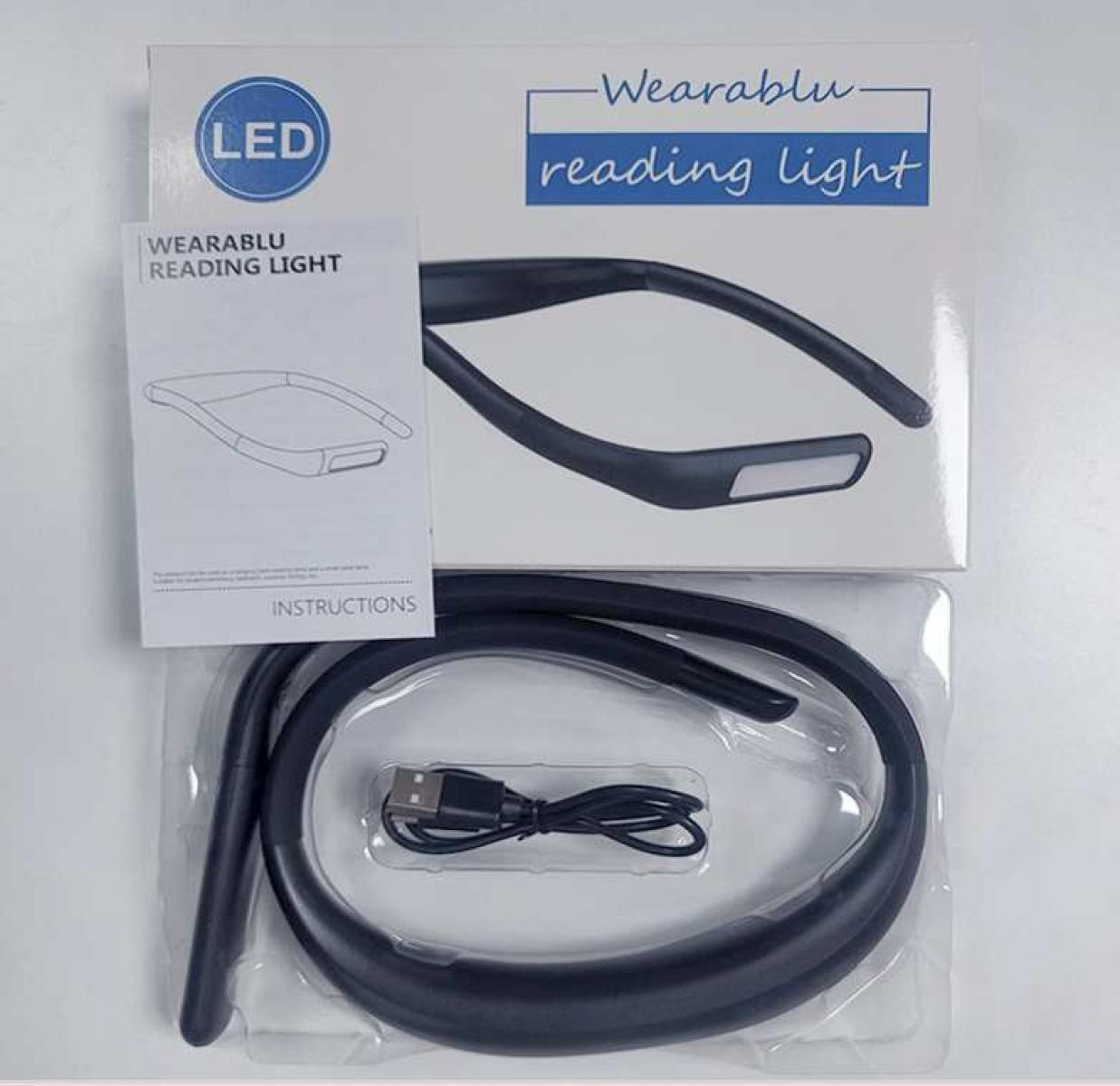 Ein Wearablu Leselicht. Es hat ein schwarzes Nackenband mit einem angebrachten Licht, eine Bedienungsanleitung und ein USB-Kabel.