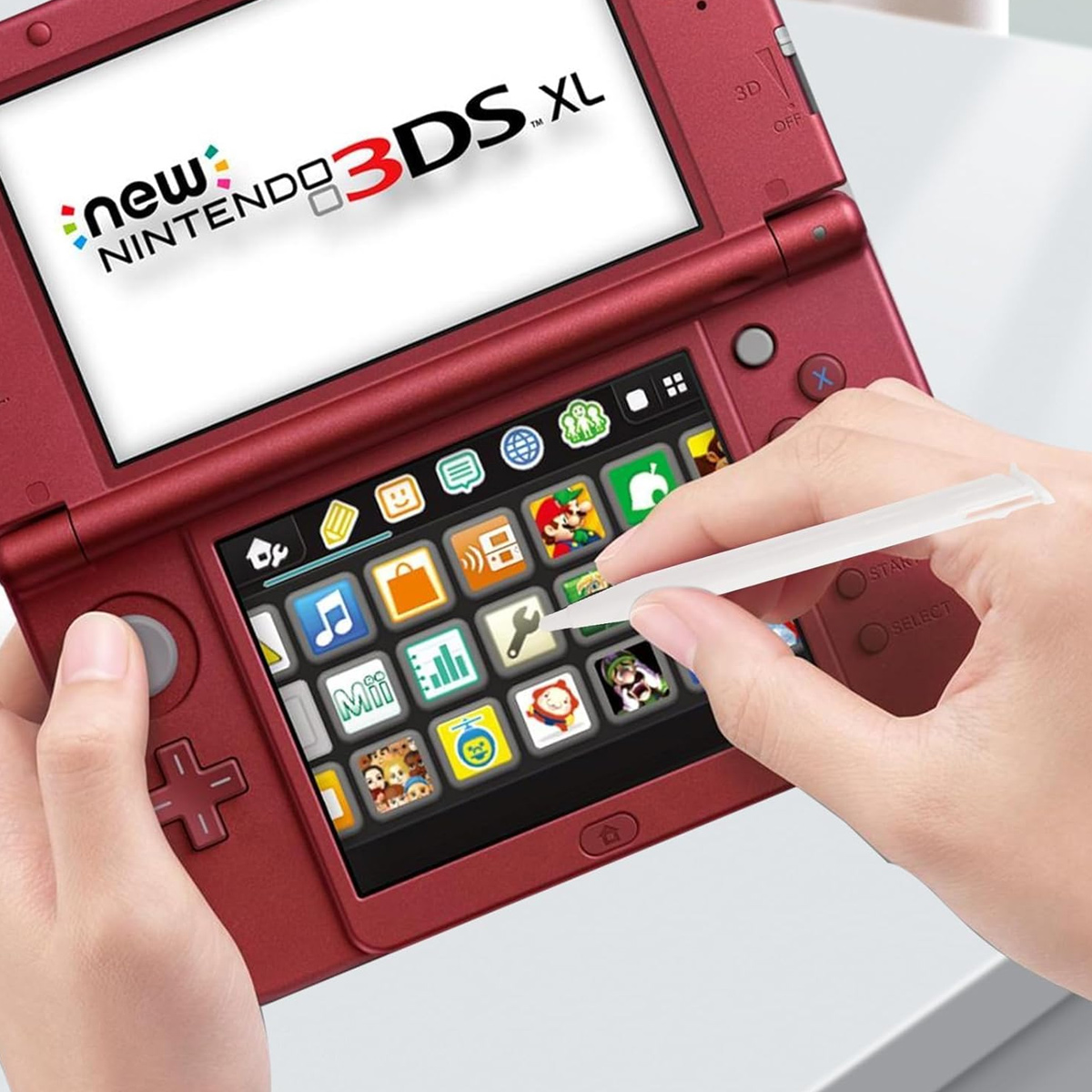 Eine Person benutzt einen Stift auf einer roten Nintendo 3DS XL-Konsole. Der Bildschirm zeigt verschiedene App-Symbole.