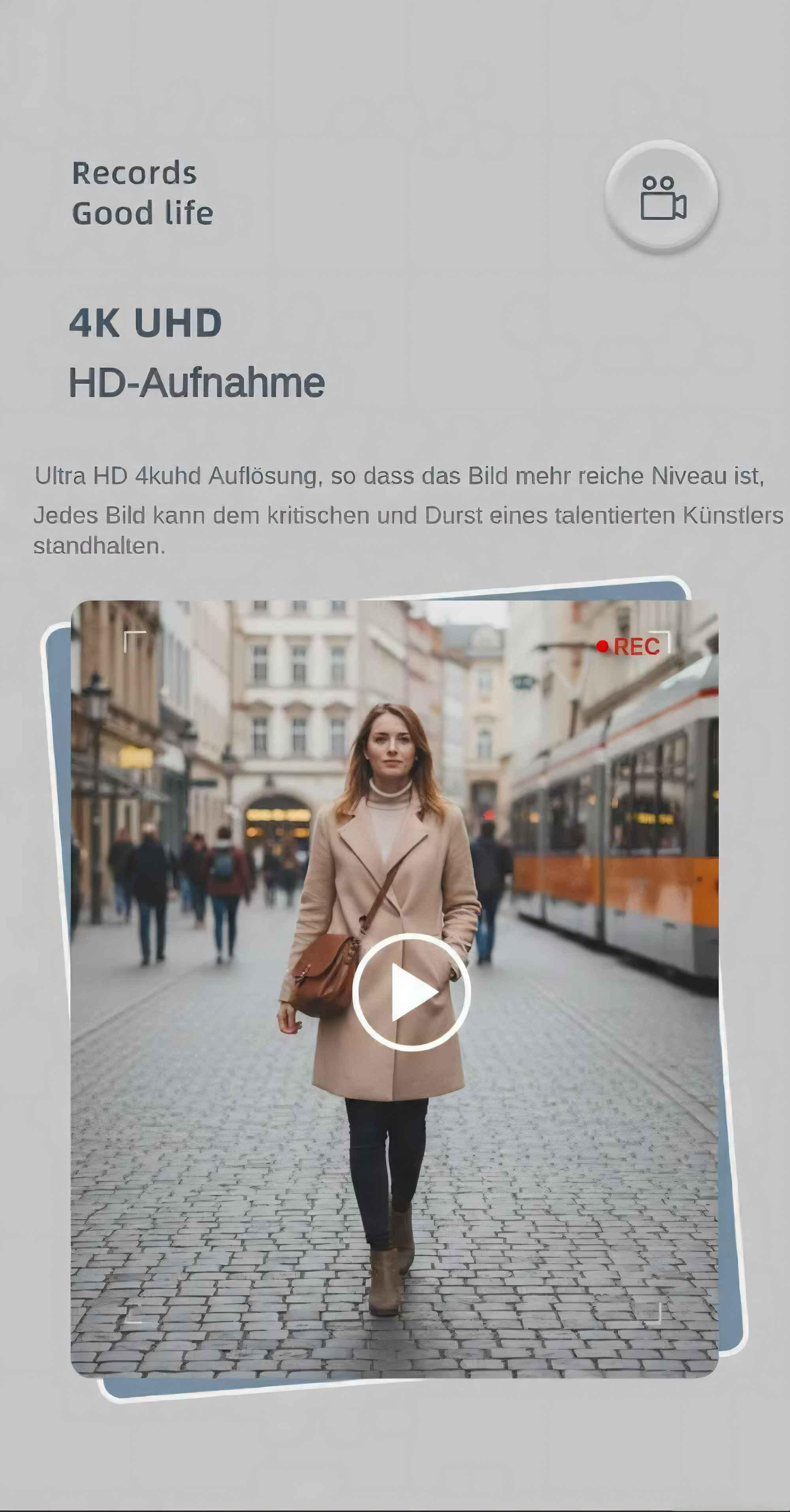 Eine Frau geht auf einer Kopfsteinpflasterstraße. Auf ihrem Mantel befindet sich eine Wiedergabetaste. Im Hintergrund ist eine Straßenbahn.