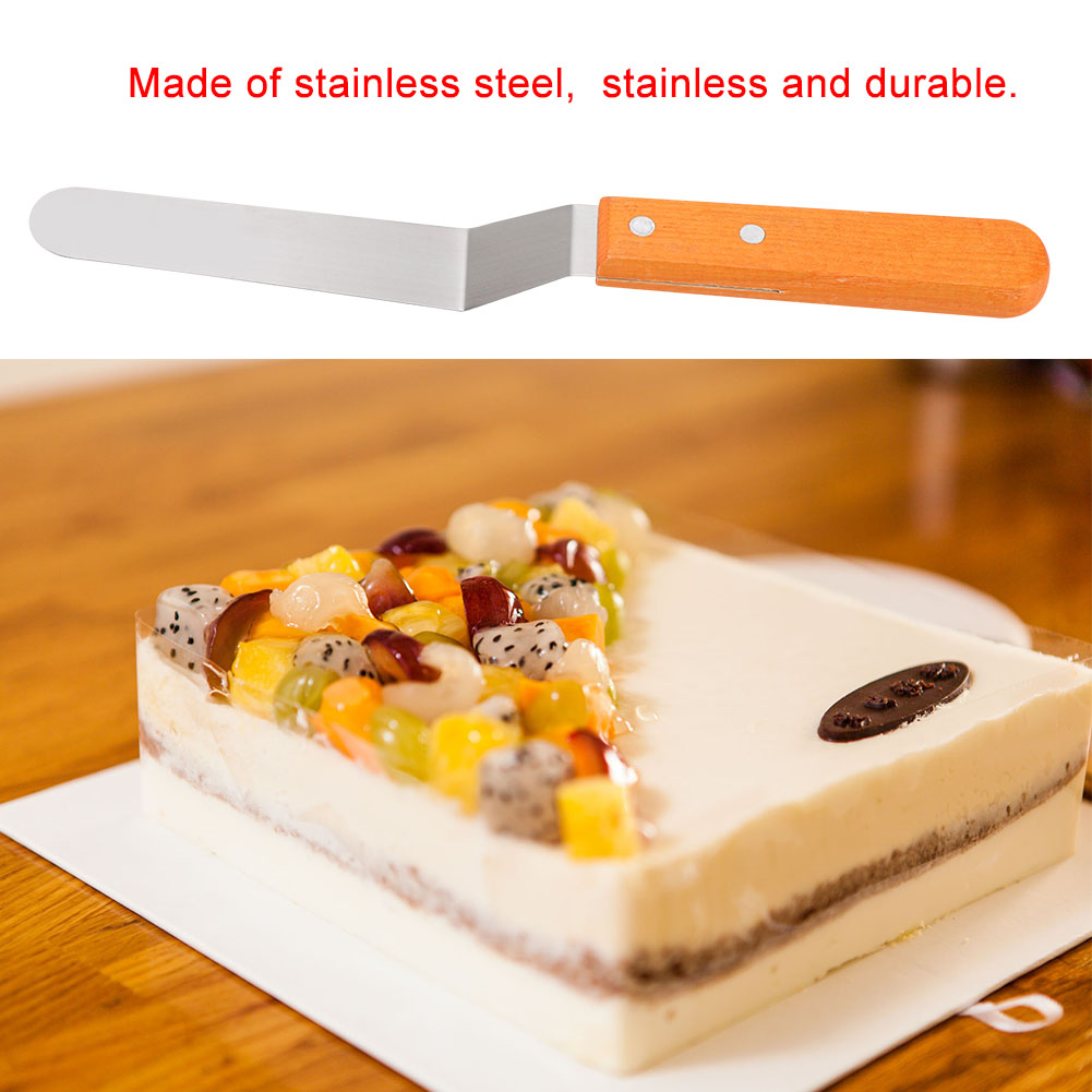 Ein Spatel mit Holzgriff und ein Kuchenstück mit Früchten. Der Kuchen hat eine dunkle Schicht und eine weiße Basis.