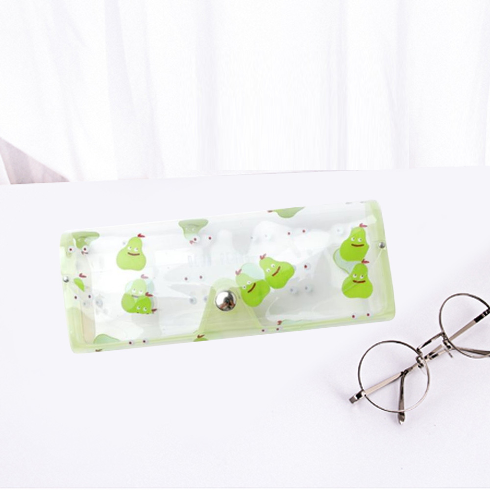 Eine transparente Brillenetui mit birnenförmigen Cartoon-Designs liegt auf einer weißen Oberfläche. Eine runde Brille befindet sich rechts.