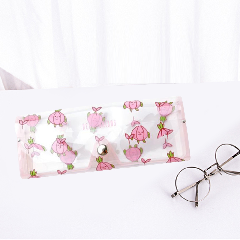 Eine klare Brillenetui mit rosa floralen Illustrationen und einer runden Brille. Das Etui liegt auf einer weißen Oberfläche.