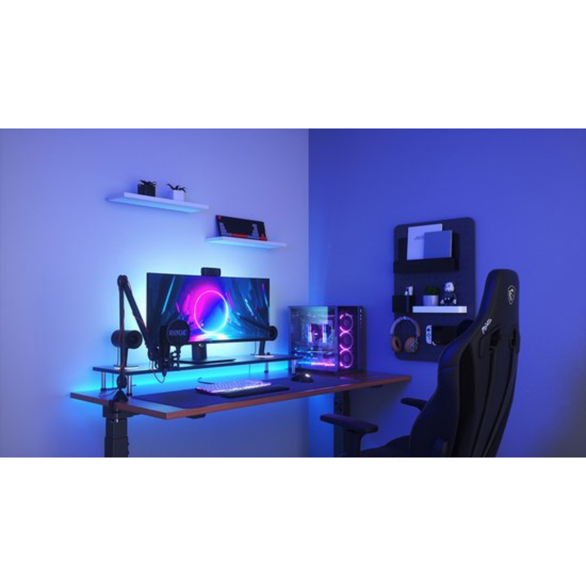 Configurazione di gioco con monitor, PC, microfono e sedia nera. La stanza ha luce blu e mensole sul muro.