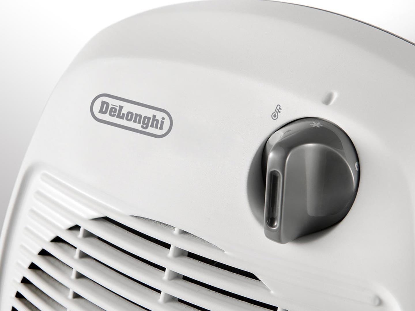 Ein weißer DeLonghi-Heizlüfter. Er hat einen grauen Drehknopf mit Temperatur- und Lüftereinstellungen. Der Markenname ist sichtbar.