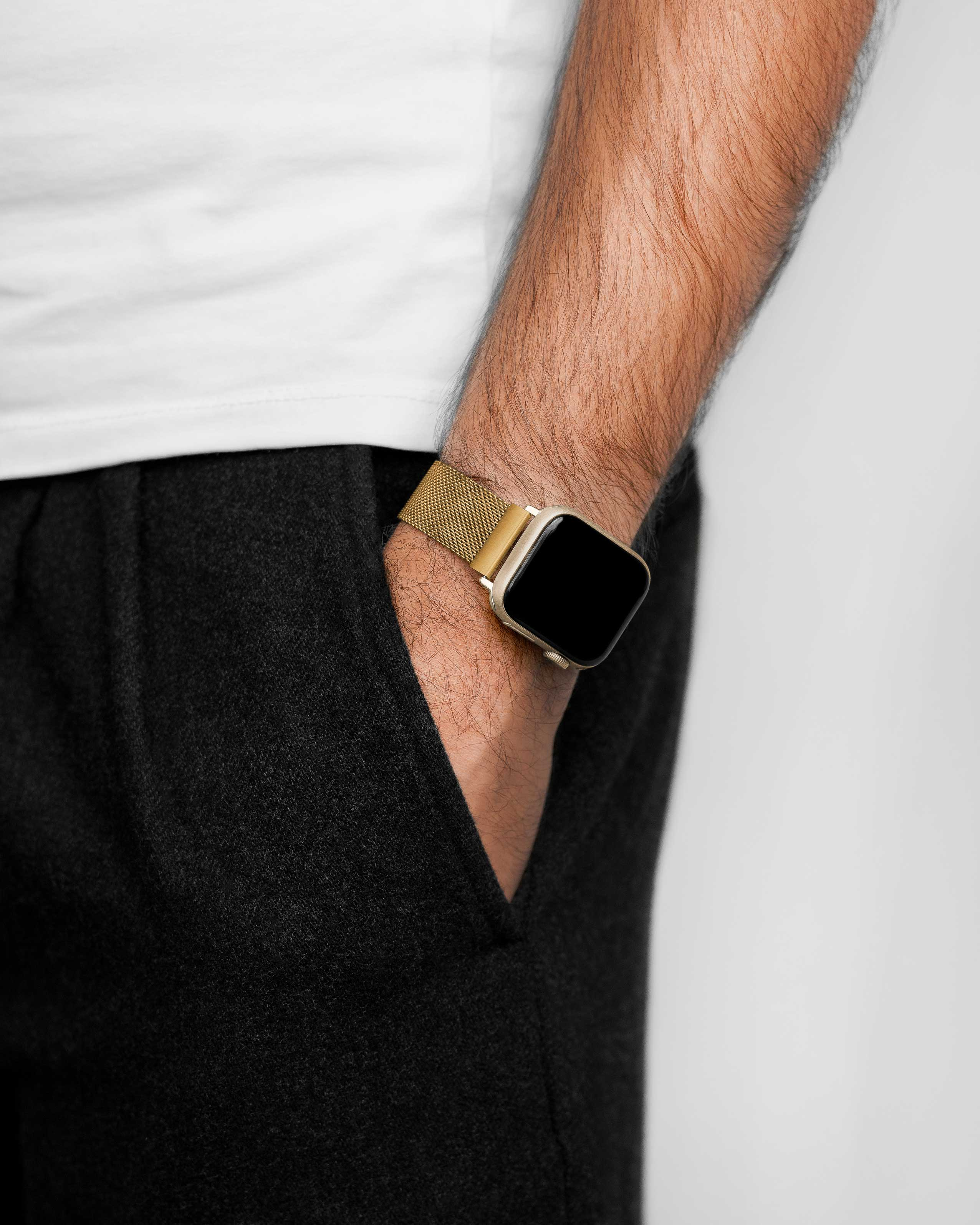Arm einer Person mit goldener Uhr. Der Arm ruht in einer dunklen Tasche. Ein weißes Hemd ist sichtbar.