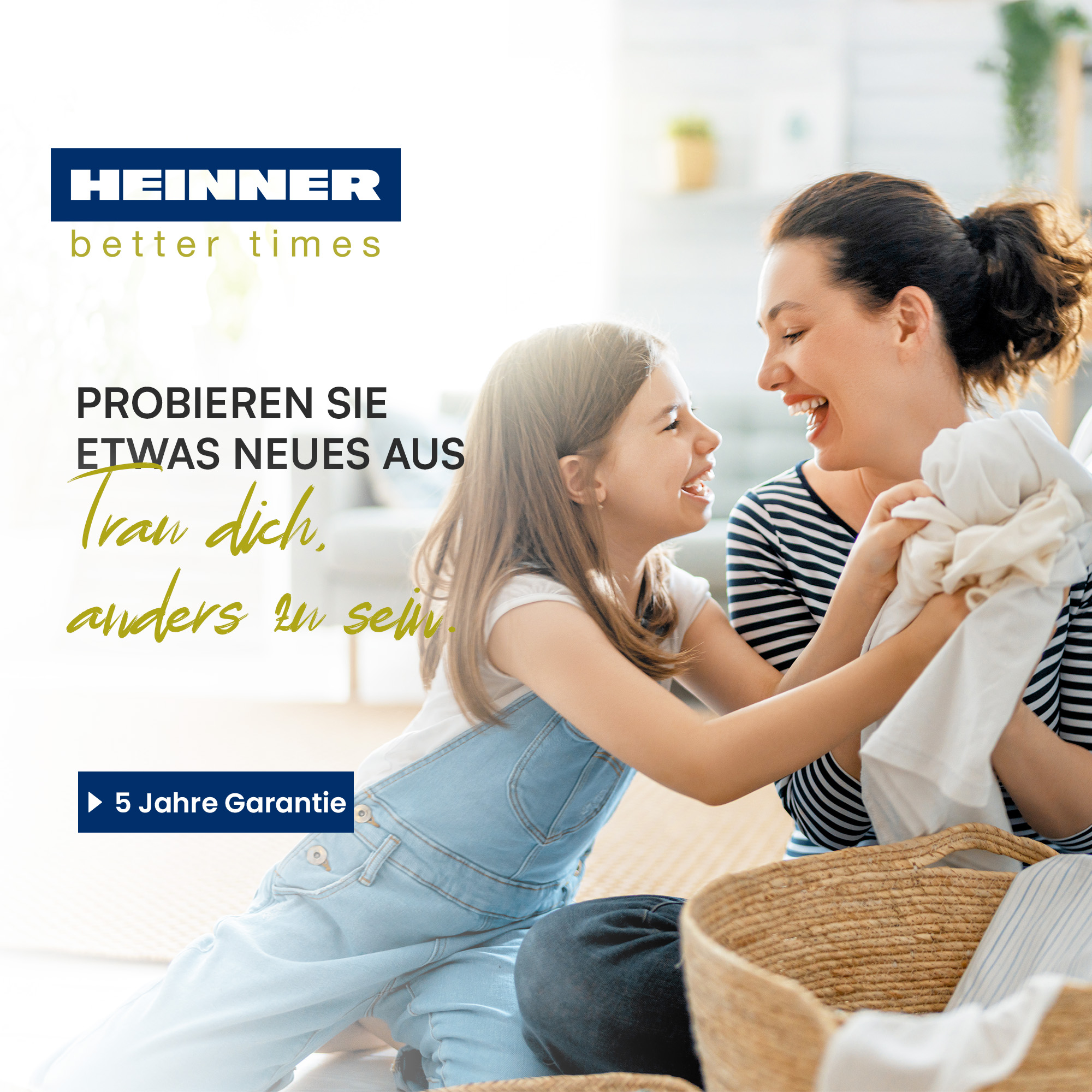 Eine Frau und ein Mädchen lachen und halten Kleidung. Ein Wäschekorb ist vor ihnen. Der Hintergrund ist verschwommen.