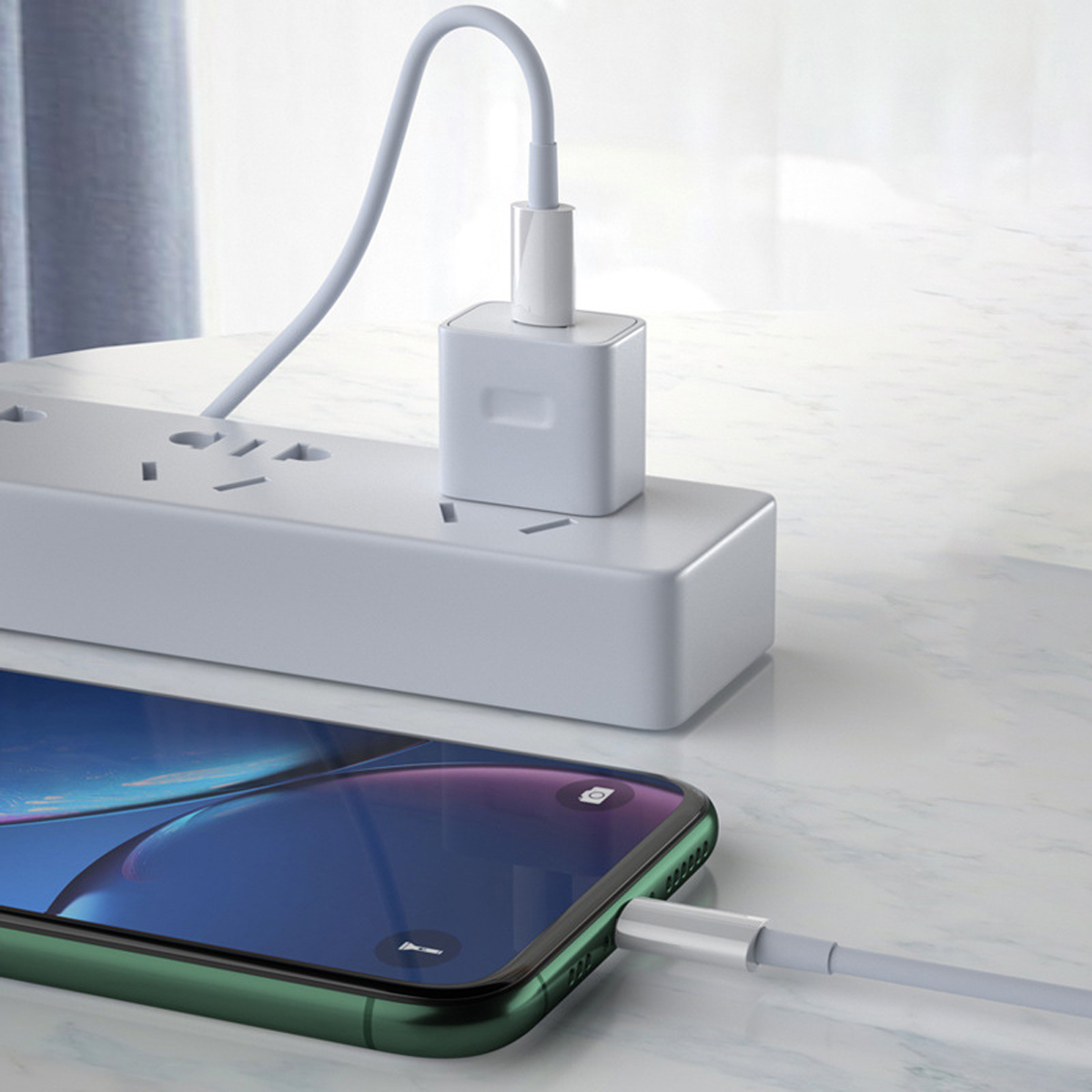 Ein Telefon wird aufgeladen. Ein weißes Ladegerät ist an eine Steckdosenleiste angeschlossen. Das Telefon ist grün und der Bildschirm ist blau.
