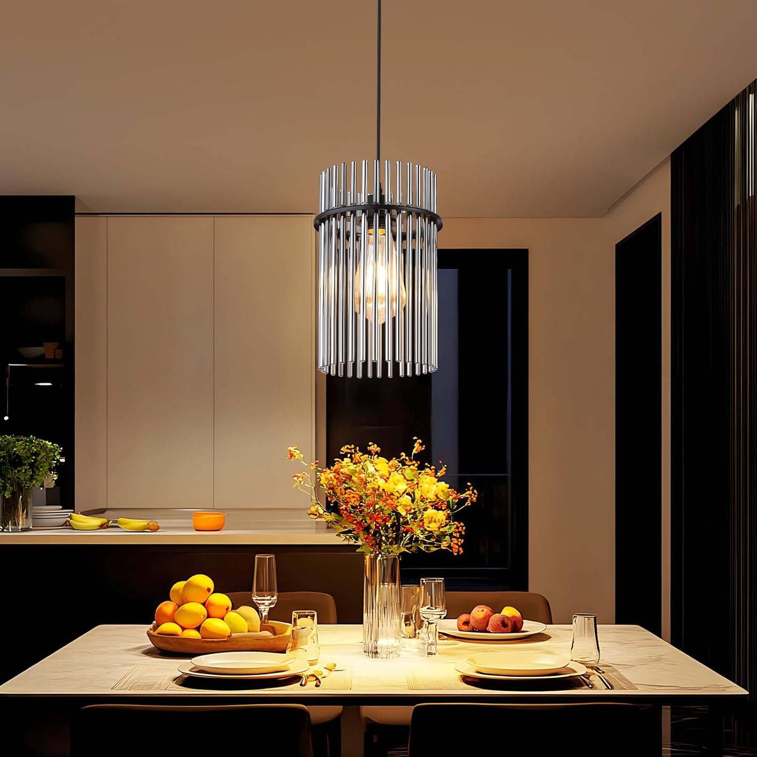 Sala da pranzo con lampadario, tavolo apparecchiato con frutta, fiori e bicchieri. Arredamento e illuminazione moderni creano atmosfera.