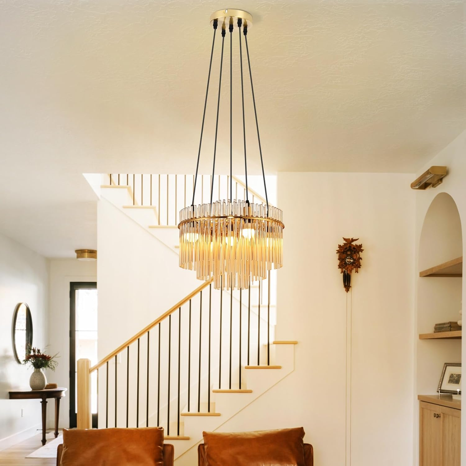 Un lampadario moderno è appeso in una stanza con scale e poltrone in pelle. Un orologio a cucù e uno specchio sono sulle pareti.