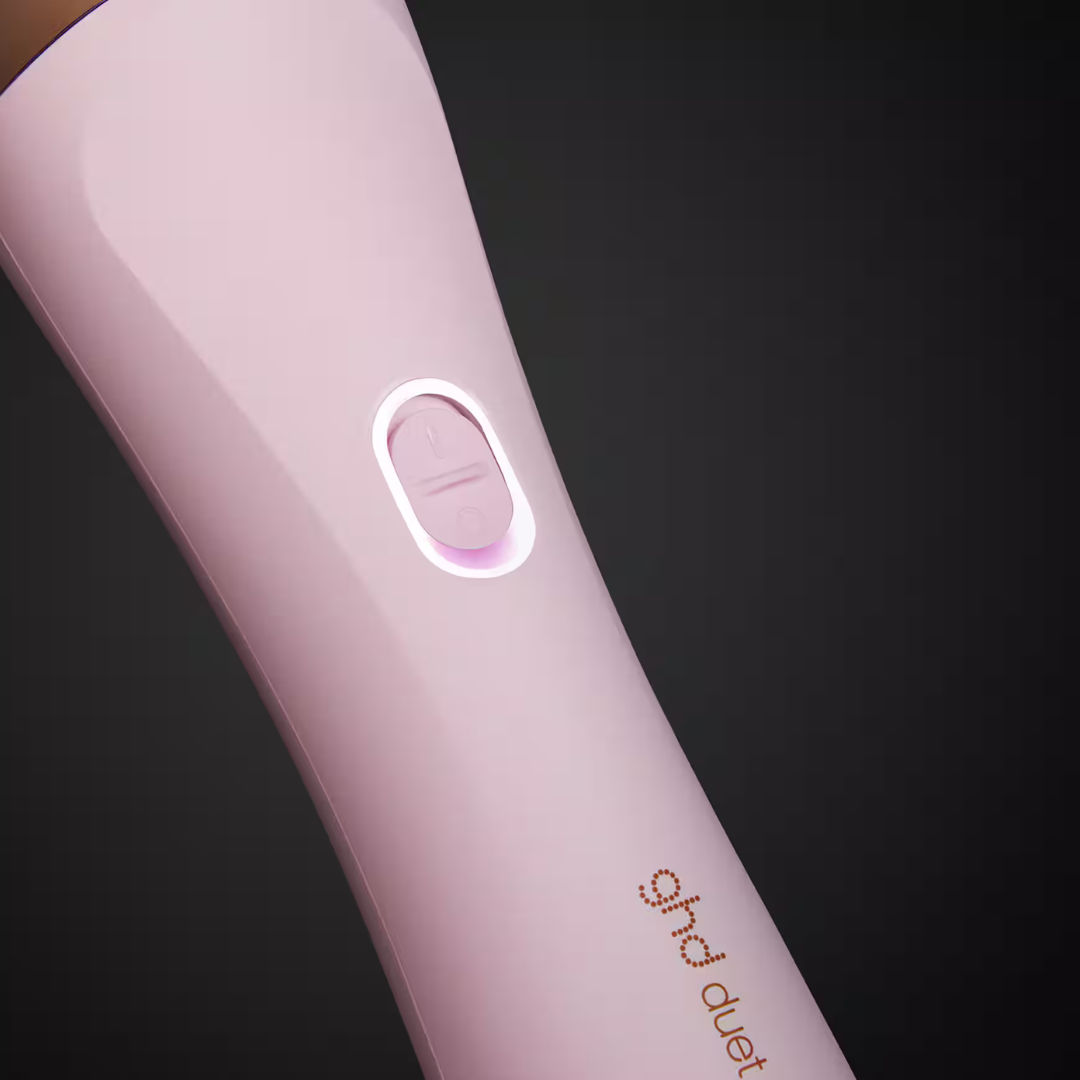 Nahaufnahme eines rosa Haarstyling-Tools. Es hat einen beleuchteten Power-Knopf. Der Markenname ist sichtbar.