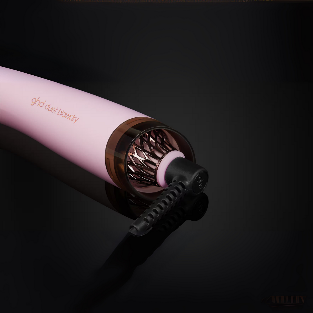 Rosa-brauner ghd Duett-Haartrockner auf einer reflektierenden schwarzen Oberfläche. Schwarzes Kabel geht vom Styler aus.
