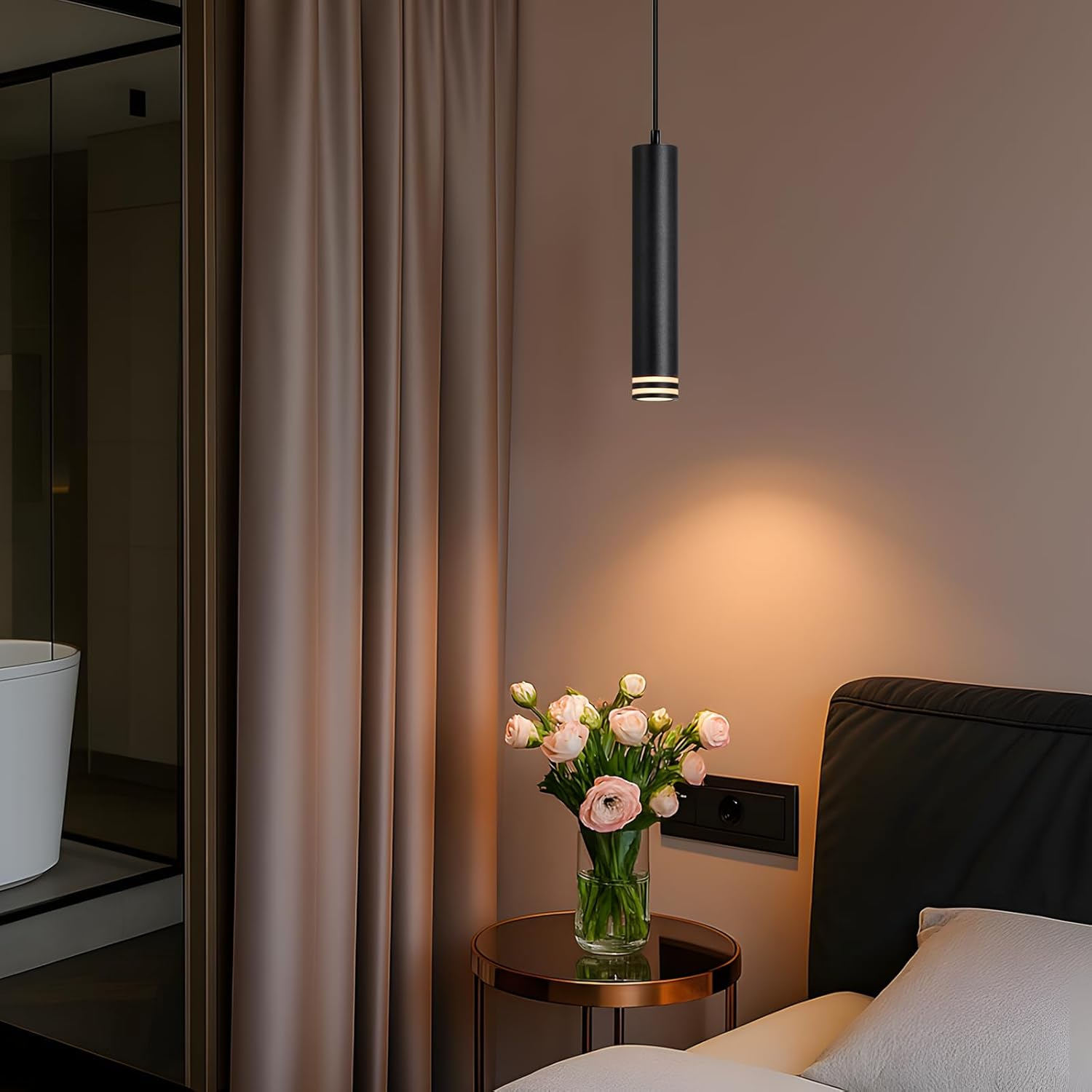 Una camera da letto moderna con una lampada a sospensione nera, fiori su un tavolo e un letto. La combinazione di colori è calda e invitante.