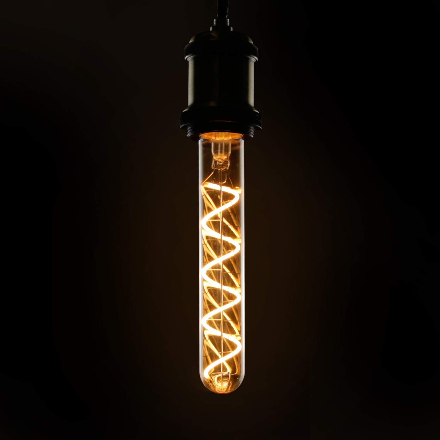 Una lampadina Edison incandescente è appesa su uno sfondo nero. La lampadina ha un filamento a spirale all'interno di un tubo di vetro trasparente.