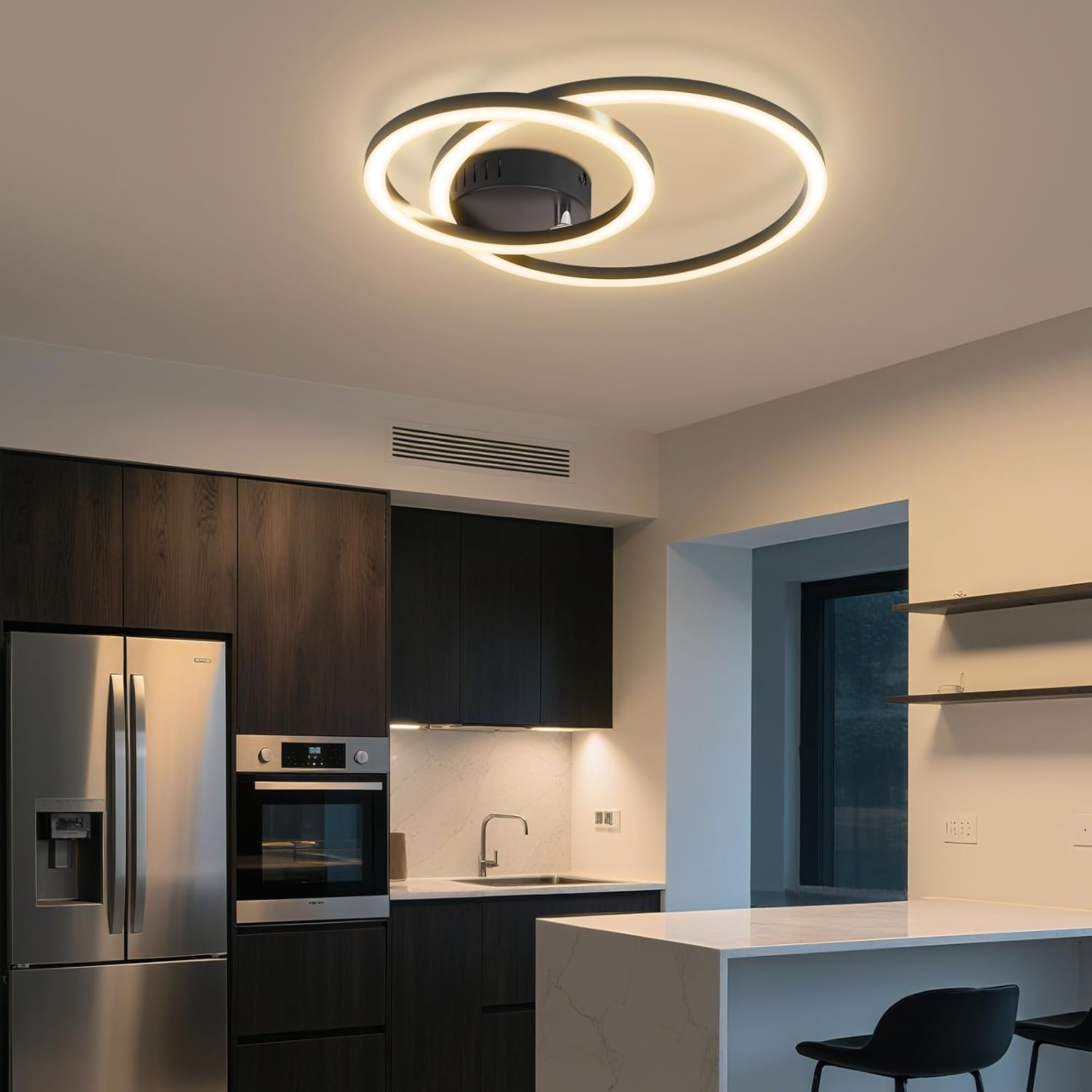 Una cucina moderna con un tema in bianco e nero. Un apparecchio di illuminazione circolare è appeso al soffitto. Gli elettrodomestici includono un frigorifero e un forno.