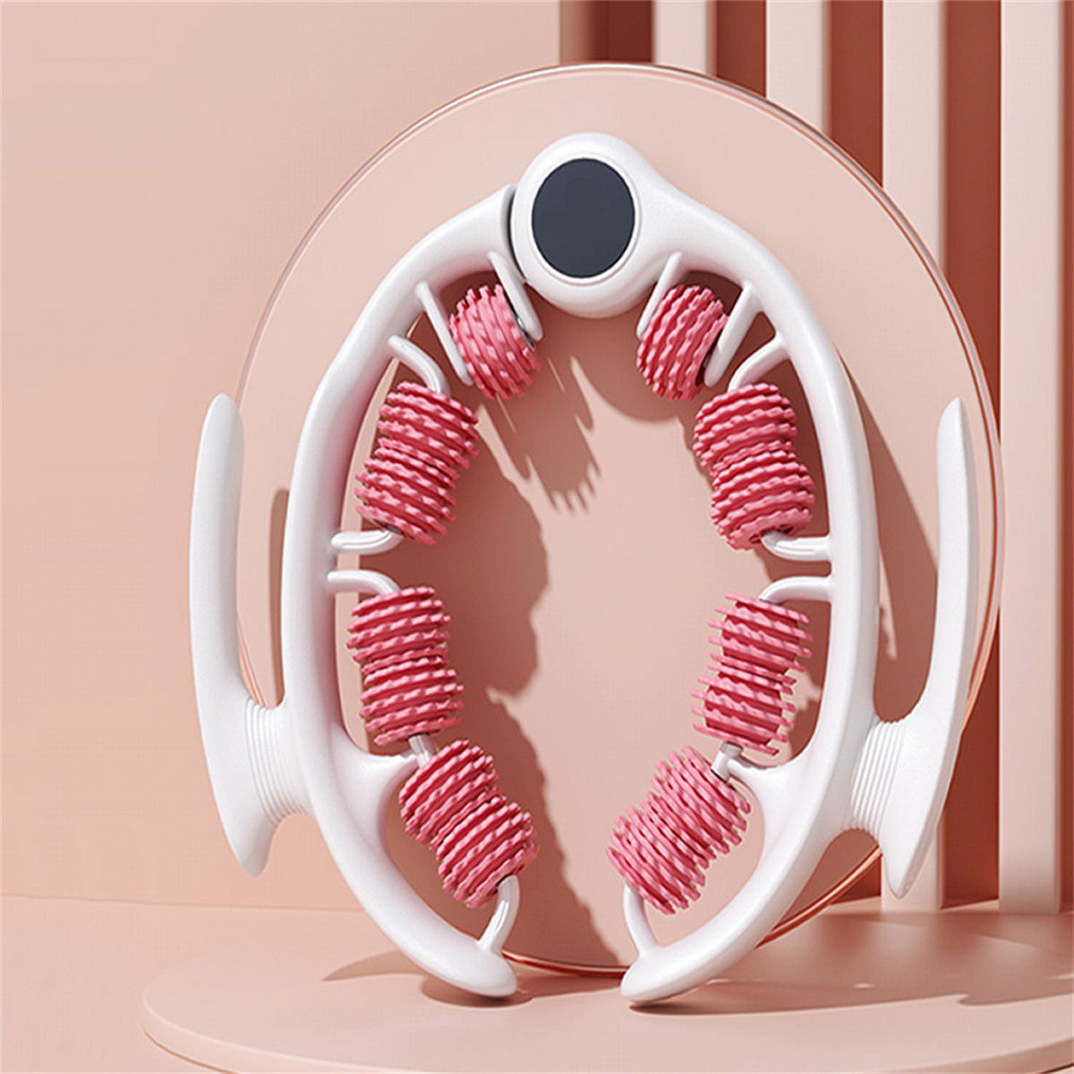 Ein weißes Massagegerät mit pinkfarbenen Rollen, kreisförmig angeordnet. Es steht auf einer pinkfarbenen Plattform vor einem weichen pinkfarbenen Hintergrund.