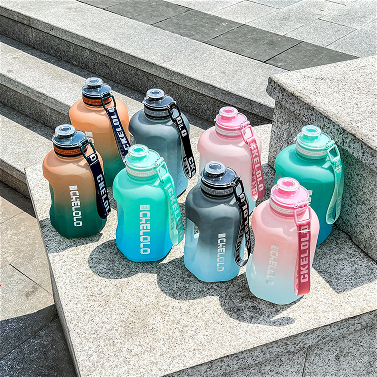 Sieben bunte Wasserflaschen stehen auf Steinstufen. Jede Flasche hat einen Riemen mit der Aufschrift 'CKELOLO'. Farben sind Grün, Rosa und Blau.