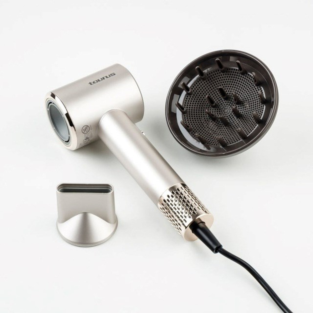 Srebrna suszarka do włosów z akcesoriami na białej powierzchni. Zawiera dyfuzor i dyszę. Widoczna jest nazwa marki 'Taurus'.