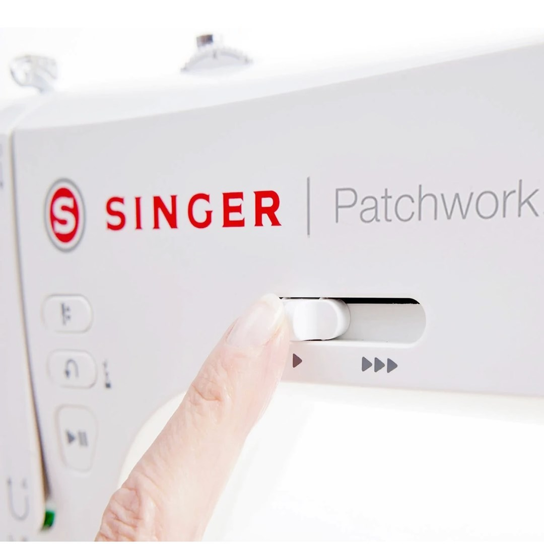 Ręka dotyka panelu sterowania maszyny do szycia. Maszyna jest biała z czerwonym logo Singer. Panel ma suwak.