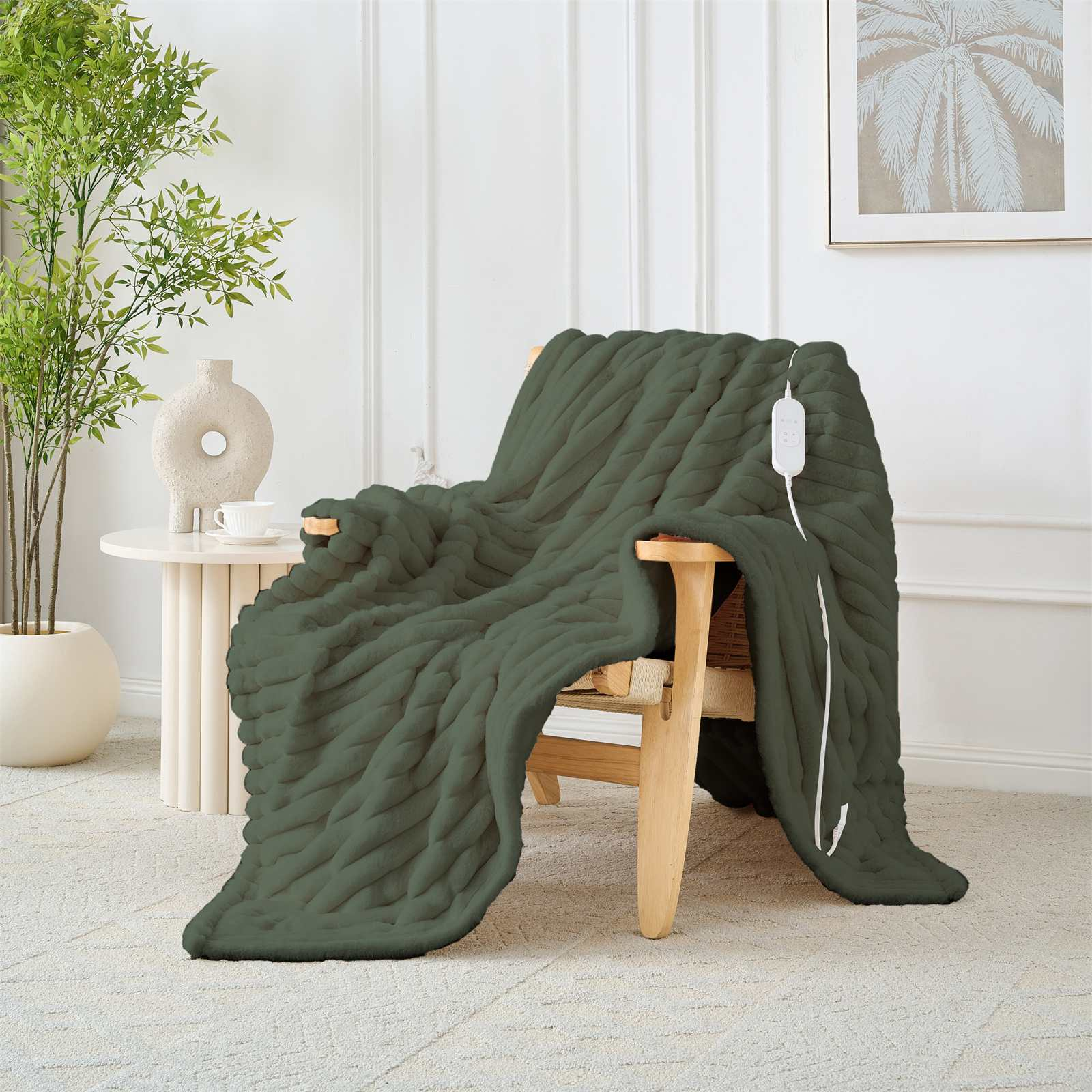 Eine grüne Heizdecke, die über einem Holzstuhl drapiert ist. Ein weißes Bedienfeld hängt an der Decke.