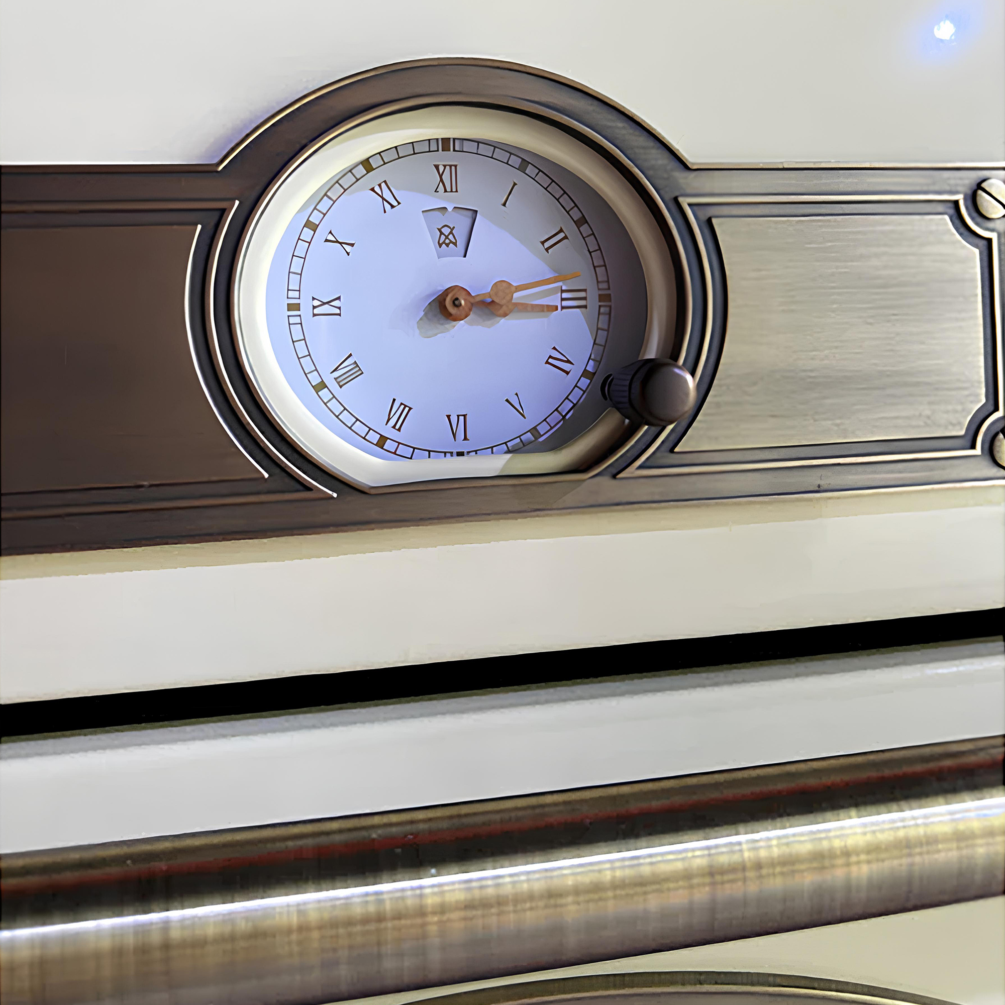 Nahaufnahme einer Uhr mit römischen Ziffern, Messingrahmen und einem schwarzen Knopf. Der Hintergrund ist cremefarben.