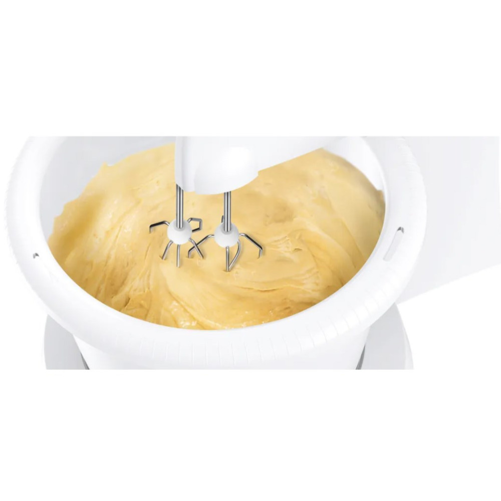 Biały mikser elektryczny miesza ciasto w białej misce. Ciasto jest żółte, mikser działa.
