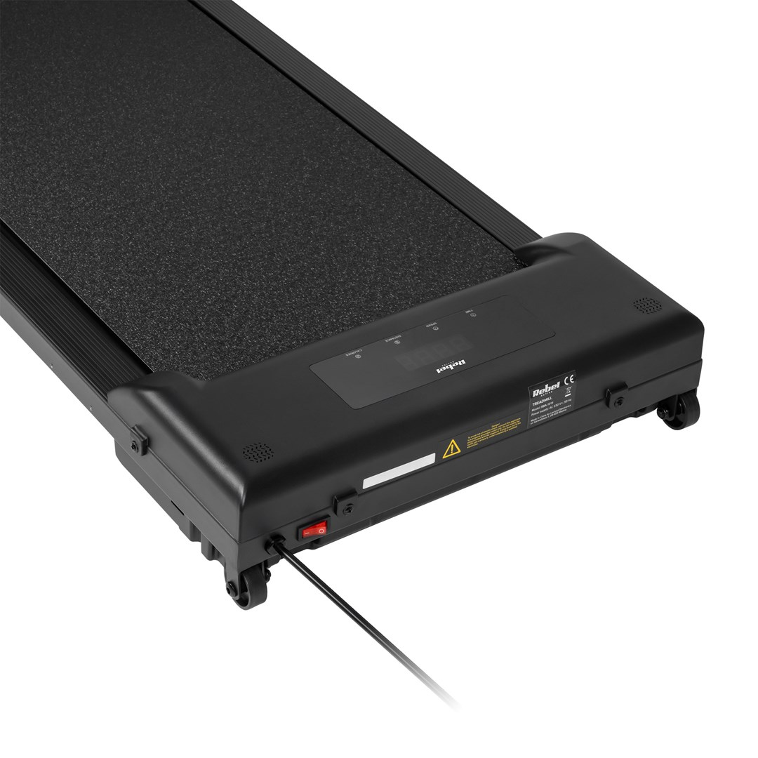 Czarna bieżnia z powierzchnią do biegania. Posiada wyświetlacz cyfrowy, przycisk zasilania i kółka. Podłączony kabel zasilający.