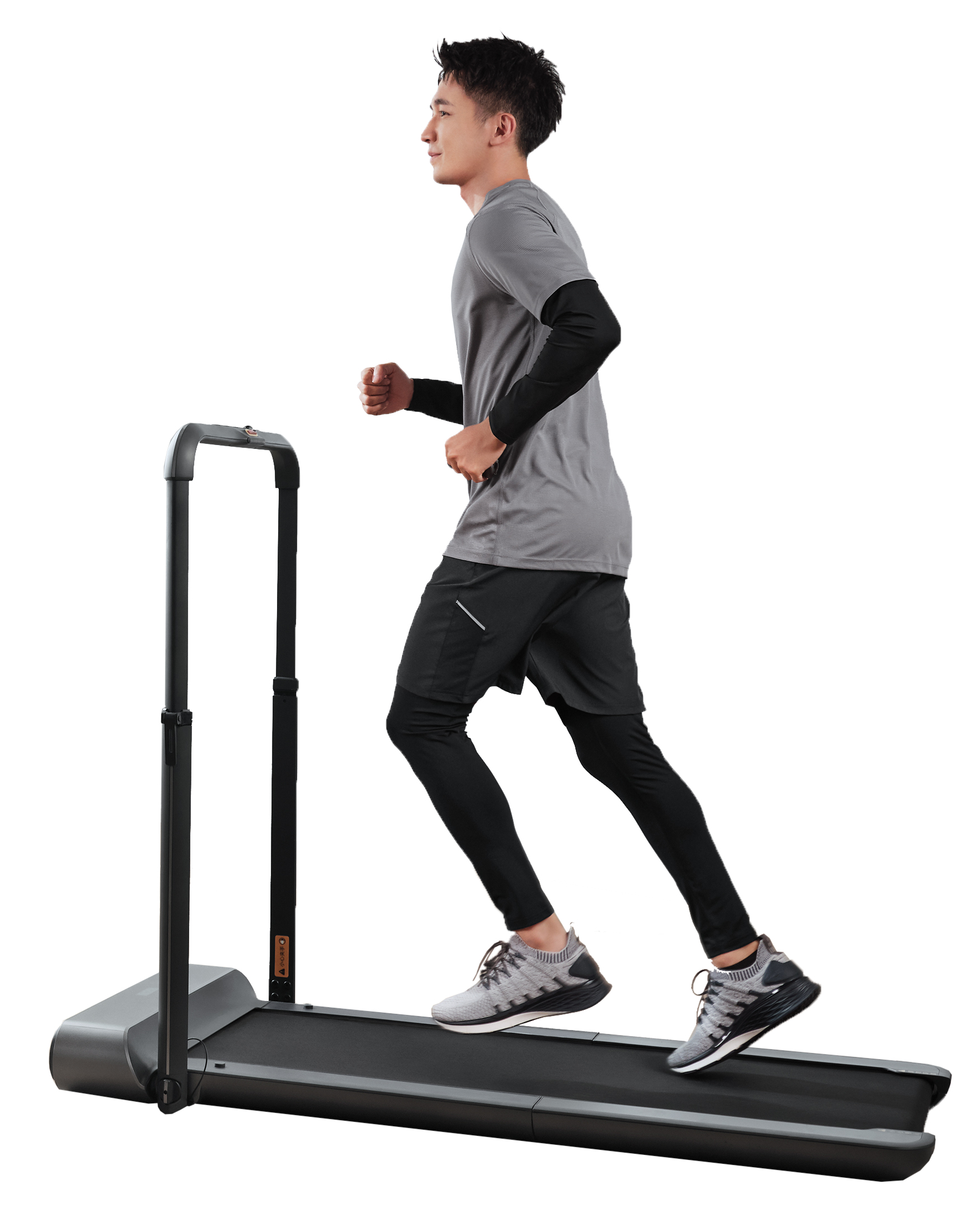 Mężczyzna biegnie na bieżni. Ma na sobie szarą koszulę, czarne szorty i legginsy, szare buty. Maszyna jest czarna.