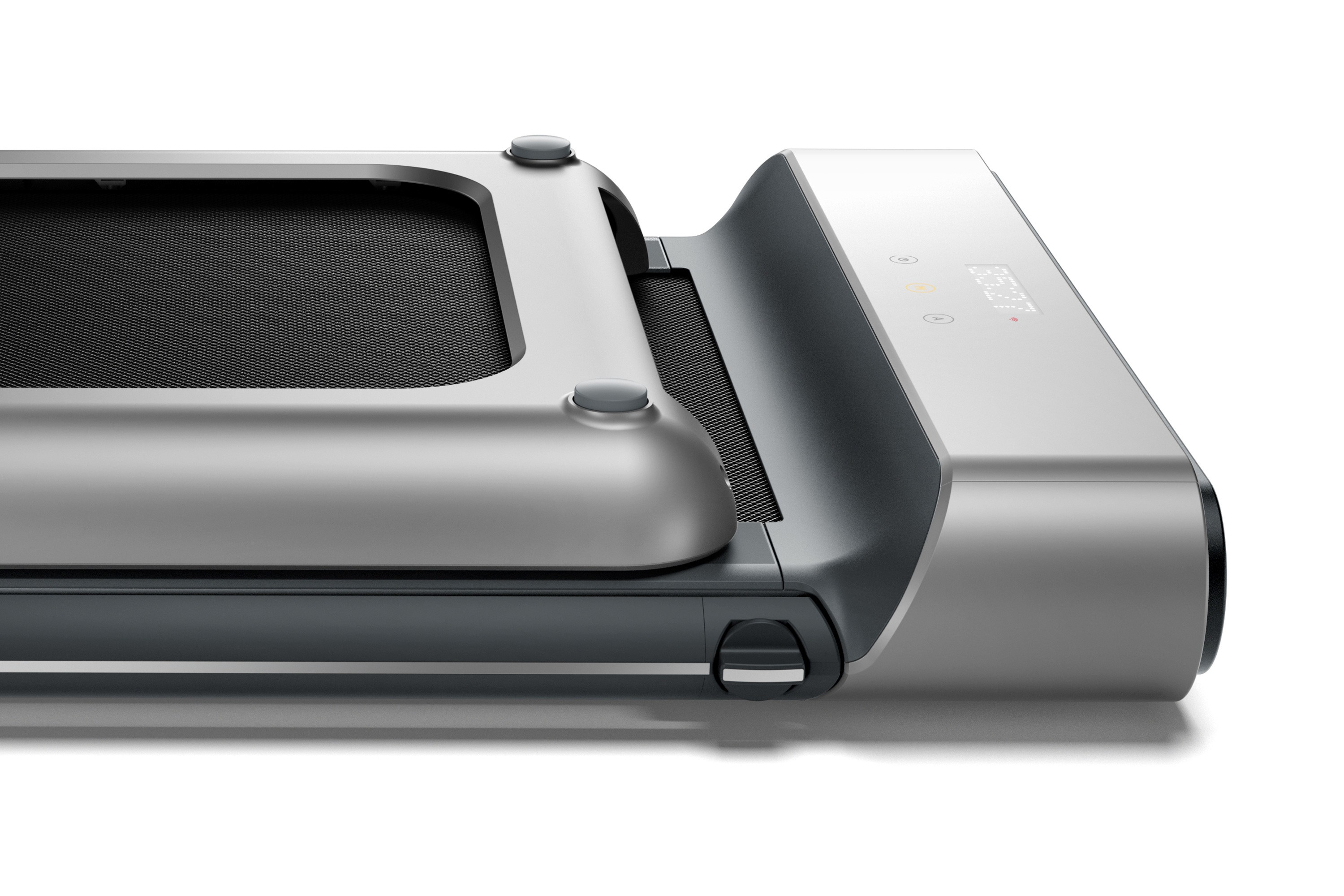 Pokazana jest srebrno-czarna bieżnia. Ma wyświetlacz i przyciski. Bieżnia jest na białym tle.