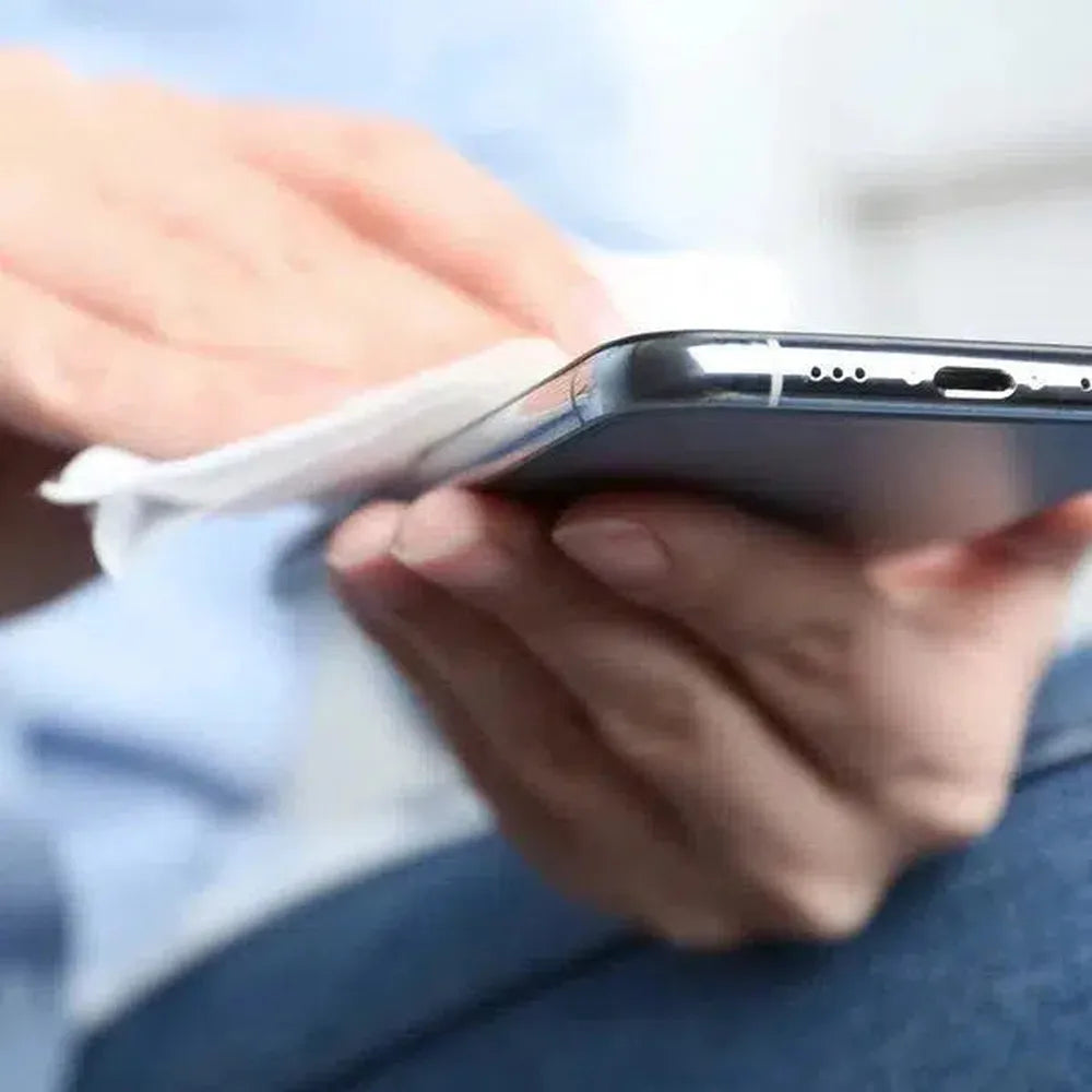 A person cleaning a black smartphone with a white wipe. The person is wearing a light blue shirt.