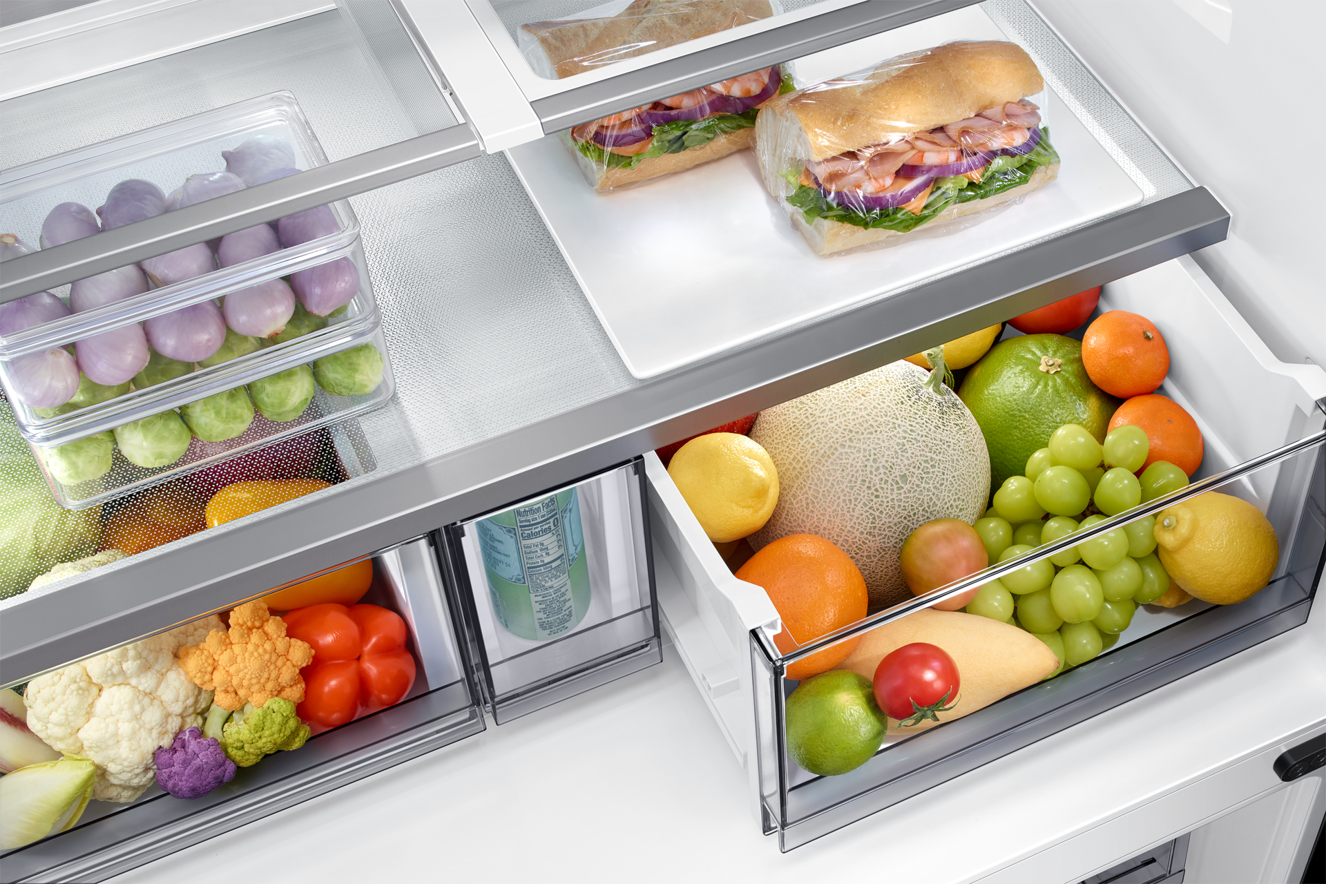 Interno del frigorifero con panini, frutta e verdura. Include melone, uva, arance, pomodori, cavolfiori e cipolle.