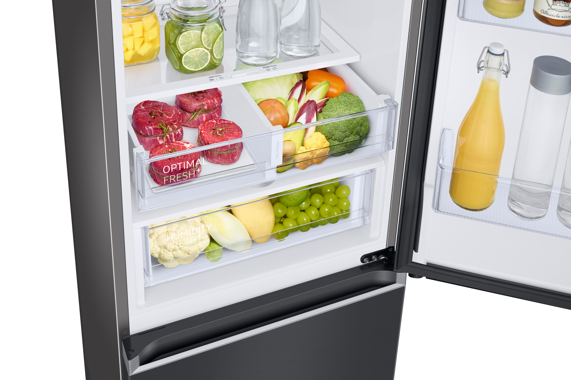 Offener Kühlschrank mit Obst, Gemüse und Fleisch. Gläser mit Limetten und Mangos. Saftflasche und klare Wasserflaschen.