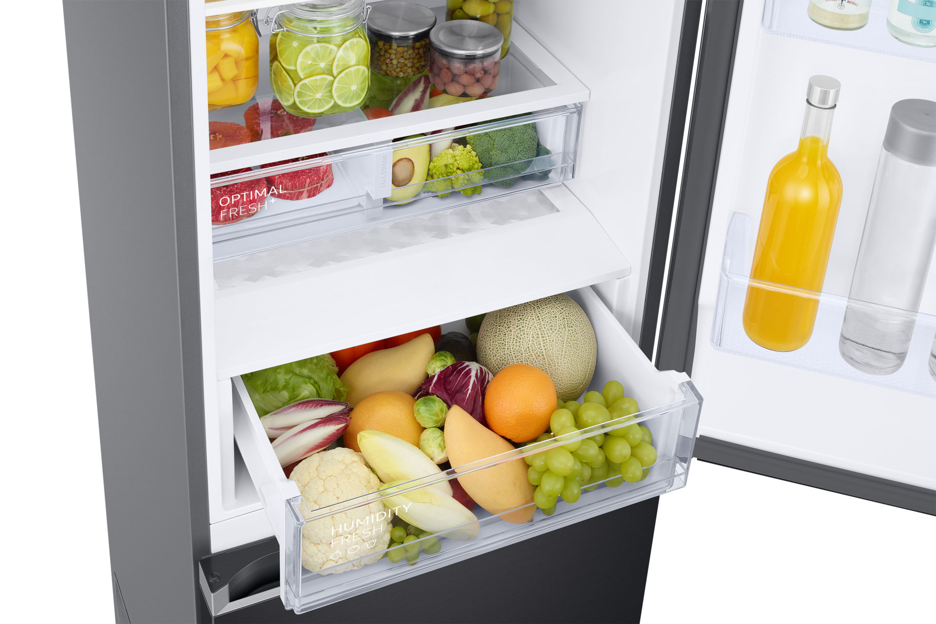 Frigorifero aperto con frutta e verdura. Include melone, uva, arance, avocado, broccoli e barattoli di cibo.