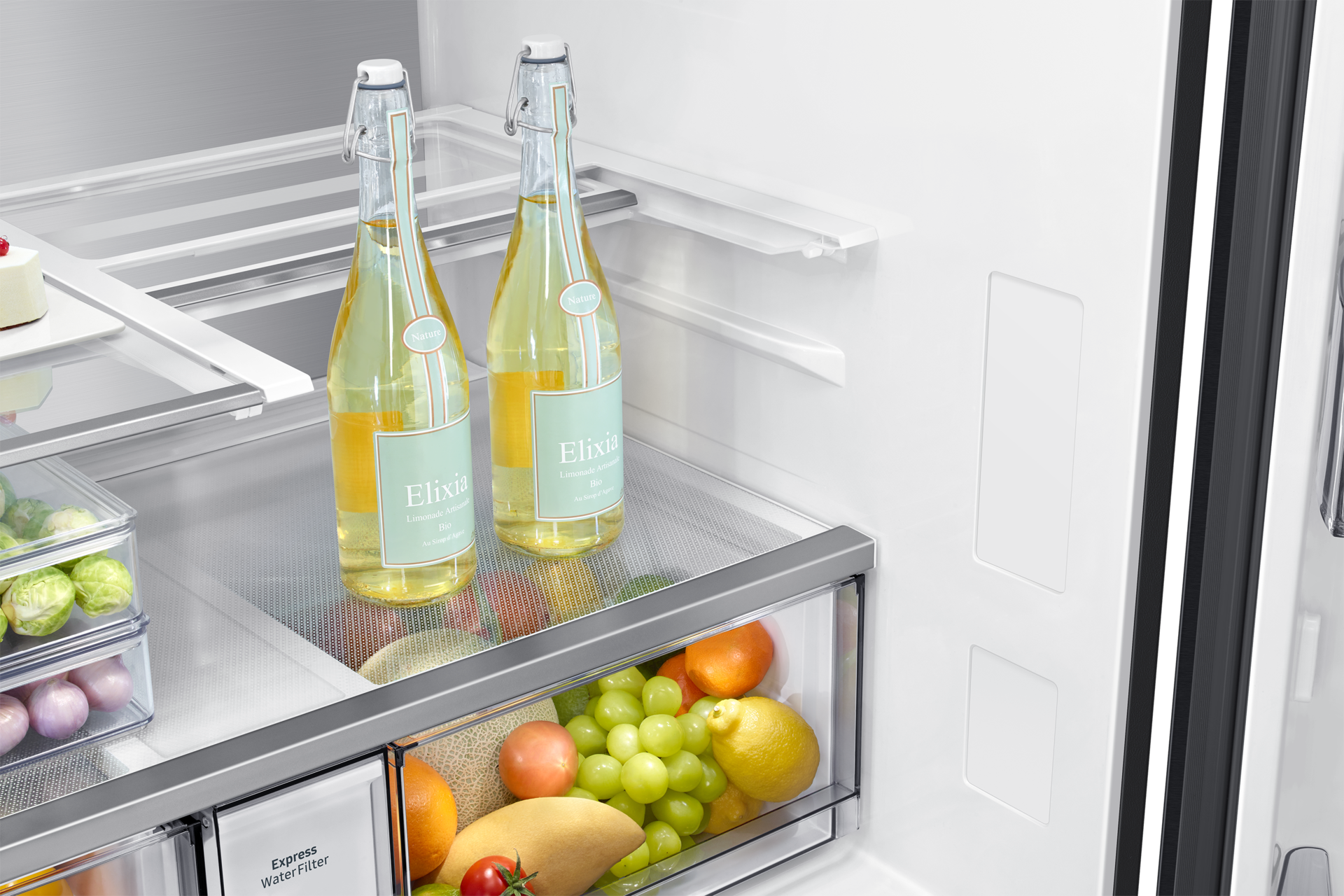 All'interno di un frigorifero, due bottiglie di limonata, frutta e verdura sono conservate nei cassetti e sugli scaffali.