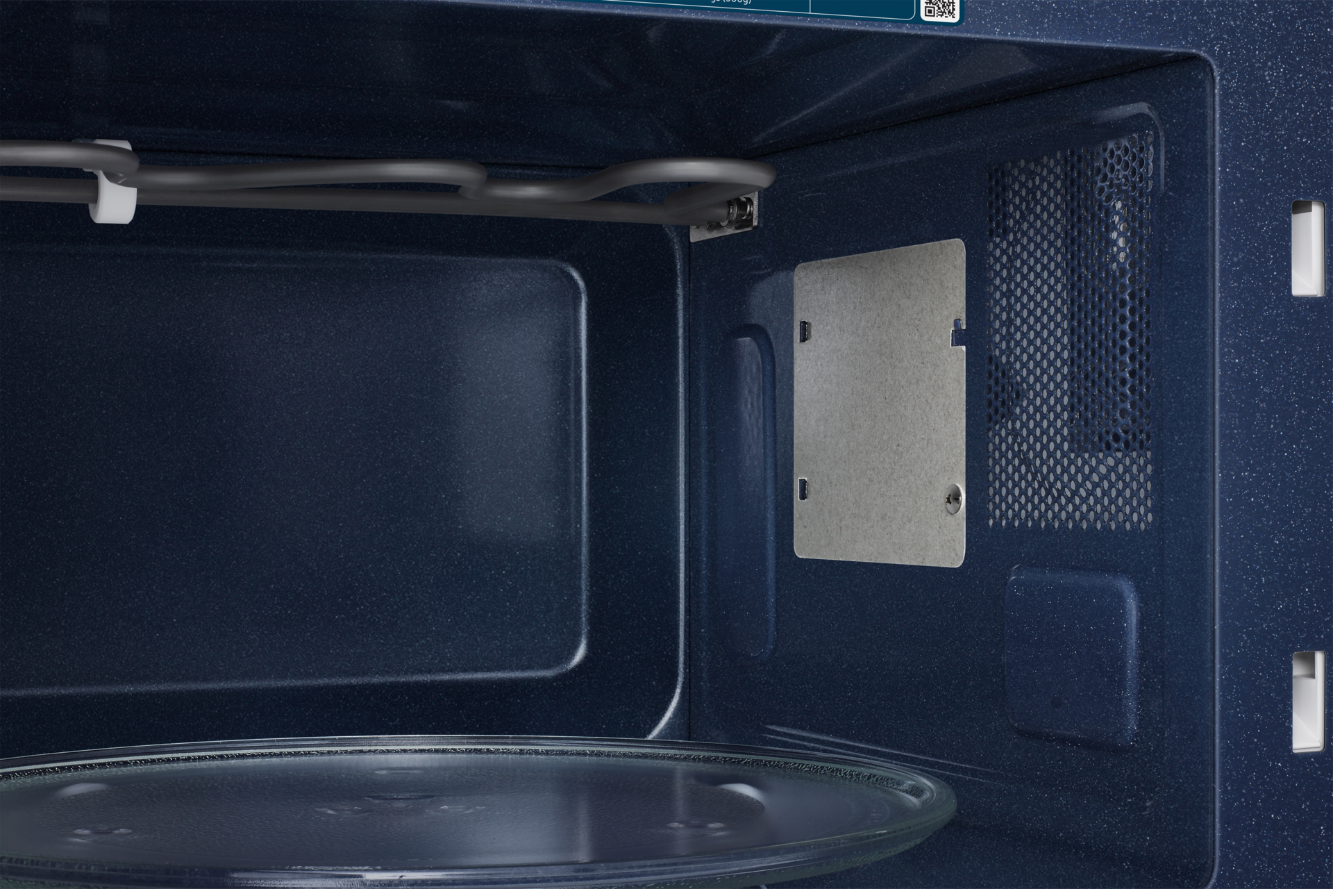 Wnętrze kuchenki mikrofalowej. Szklana płyta na dole. Wnętrze jest ciemnoniebieskie, z elementem grzejnym.