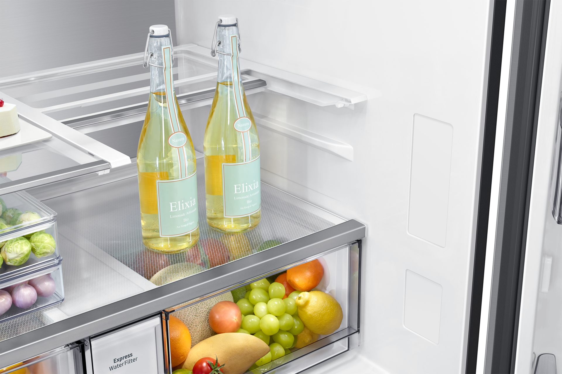 All'interno di un frigorifero, sono visibili due bottiglie di limonata e frutta come uva, arance e limoni.