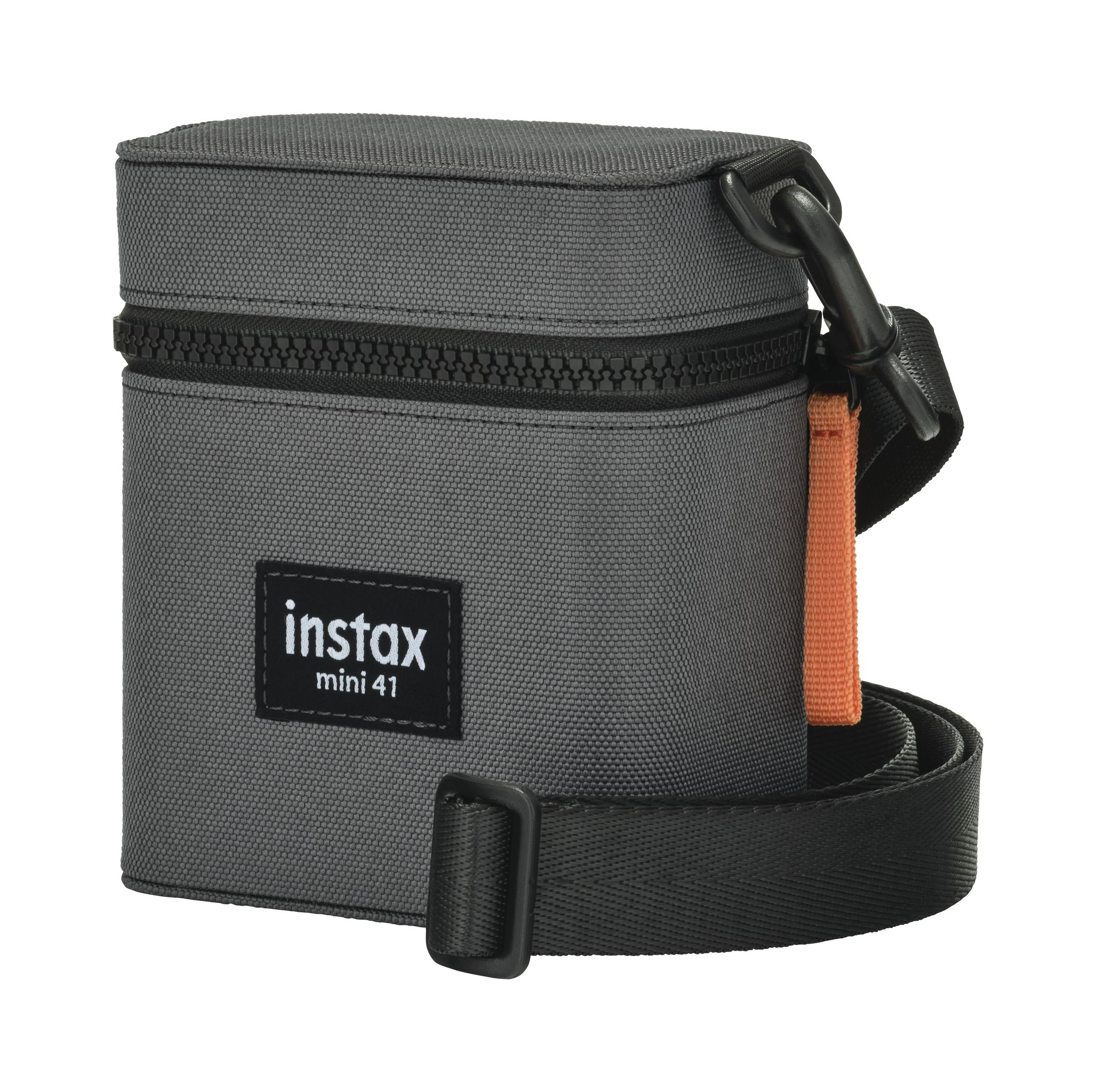 Eine graue Instax mini 41 Kameratasche mit schwarzem Reißverschluss, Riemen und Griff. Sie hat ein orangefarbenes Riemendetail.