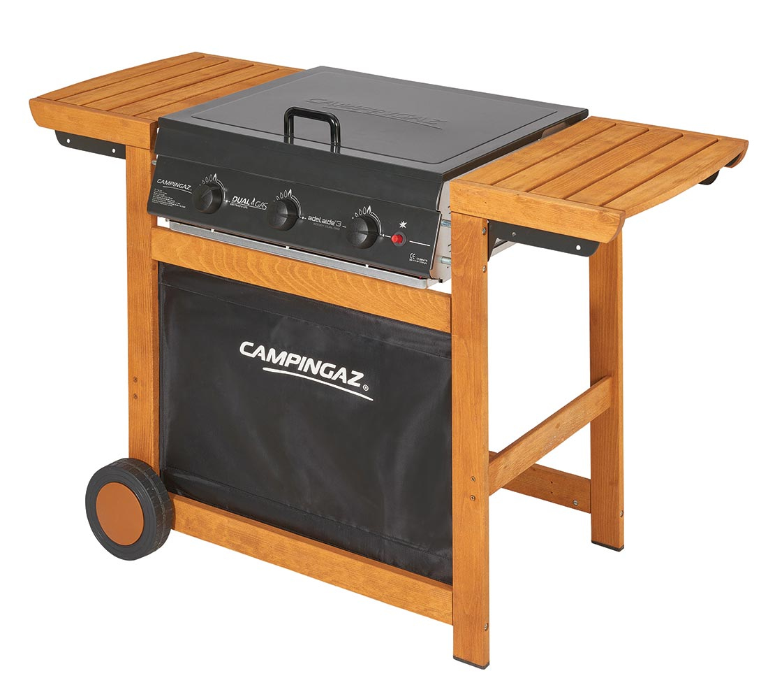 Un barbecue in legno da esterno con superficie di cottura nera, tavoli laterali e borsa portaoggetti nera. Una ruota è visibile.