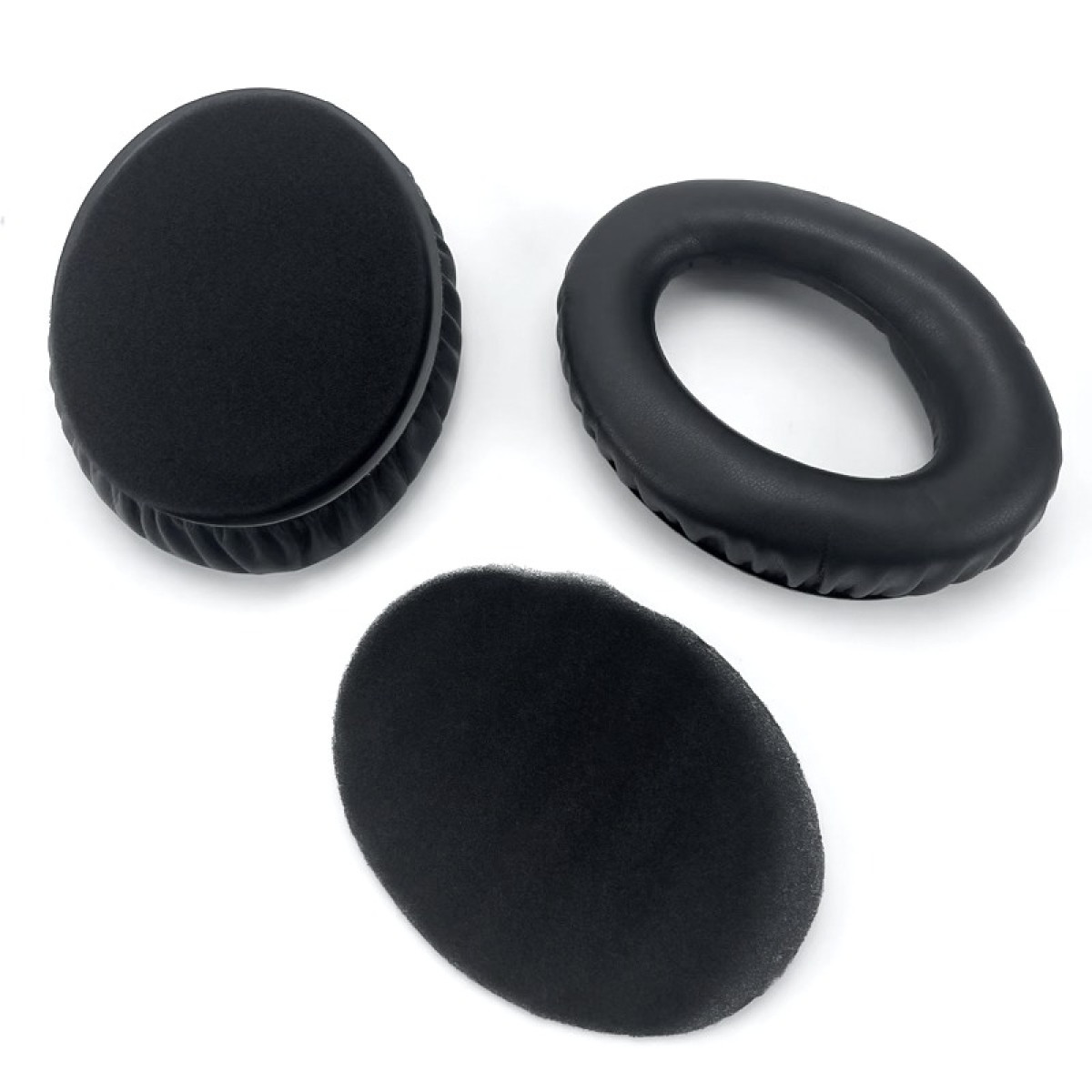 Drie zwarte oorkussens voor hoofdtelefoons op een wit oppervlak. Eén is een volledige cirkel, een andere ovaal en één een ring.
