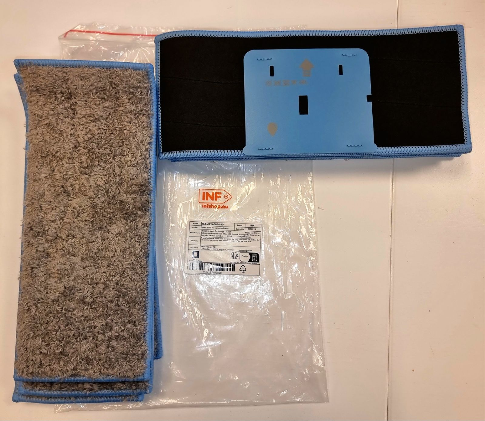 Artykuły czyszczące: głowica mopa, nakładka do mopa oraz niebieski plastikowy element z czarnym tyłem i plastikowa torba z tekstem.