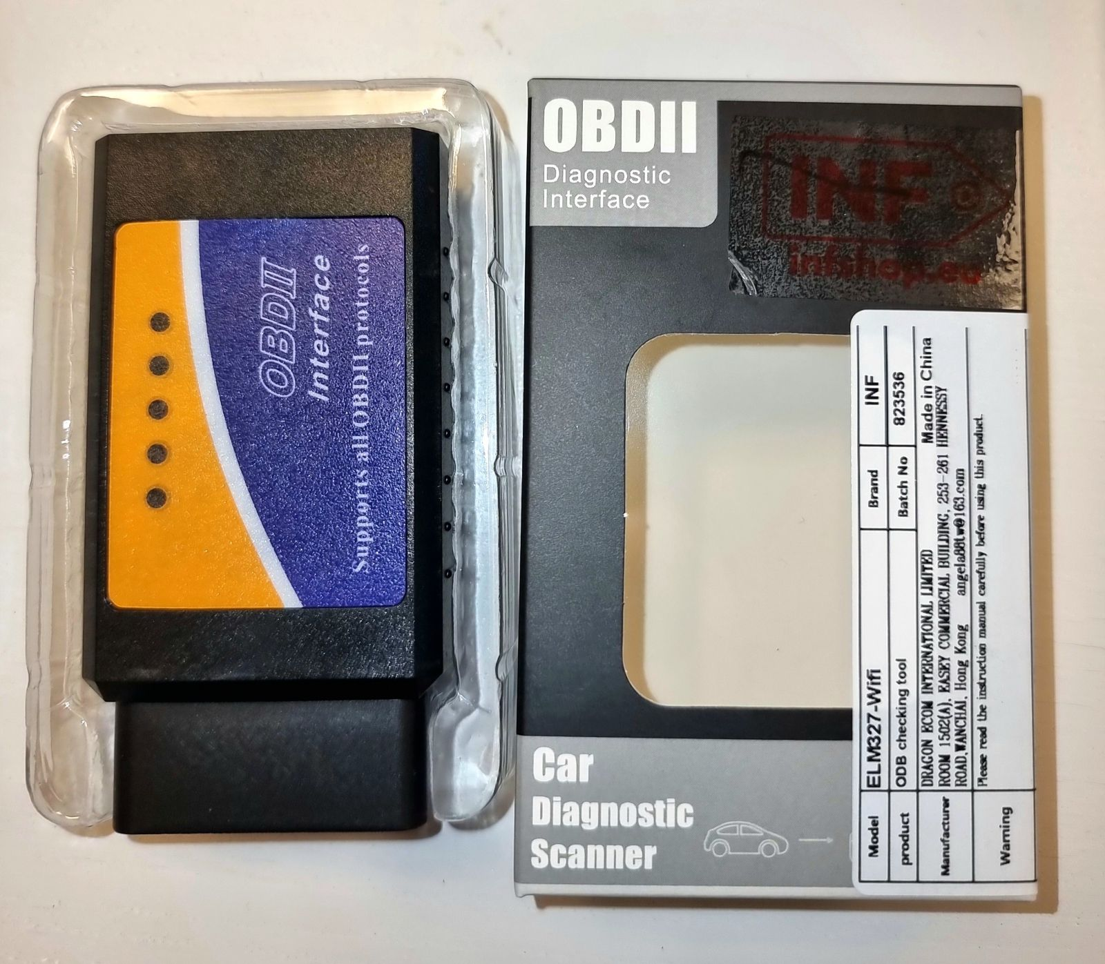 Skaner diagnostyczny OBDII w przezroczystym plastikowym opakowaniu, obok pudełka z napisem 'OBDII Diagnostic Interface' i 'Car Diagnostic Scanner'.