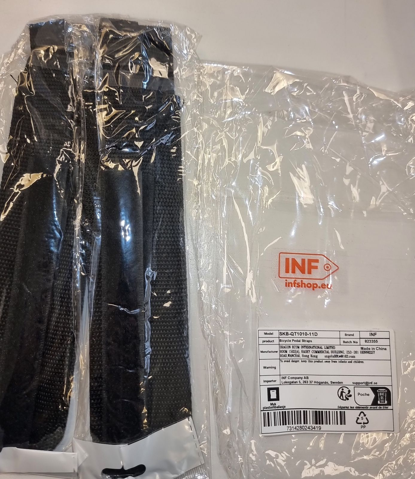 Schwarze Fahrradpedalriemen in Kunststoffverpackung. Ein Etikett mit Produktdetails ist sichtbar. Die Verpackung ist transparent.
