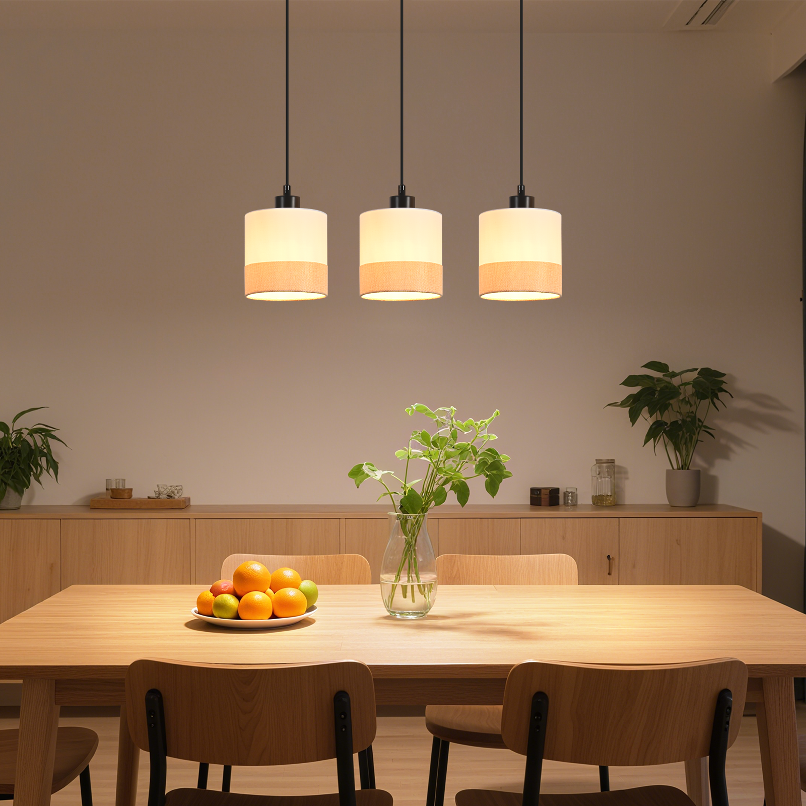 Esszimmer mit Holztisch, Stühlen, Obstschale, Vase mit Pflanzen und drei Hängelampen.