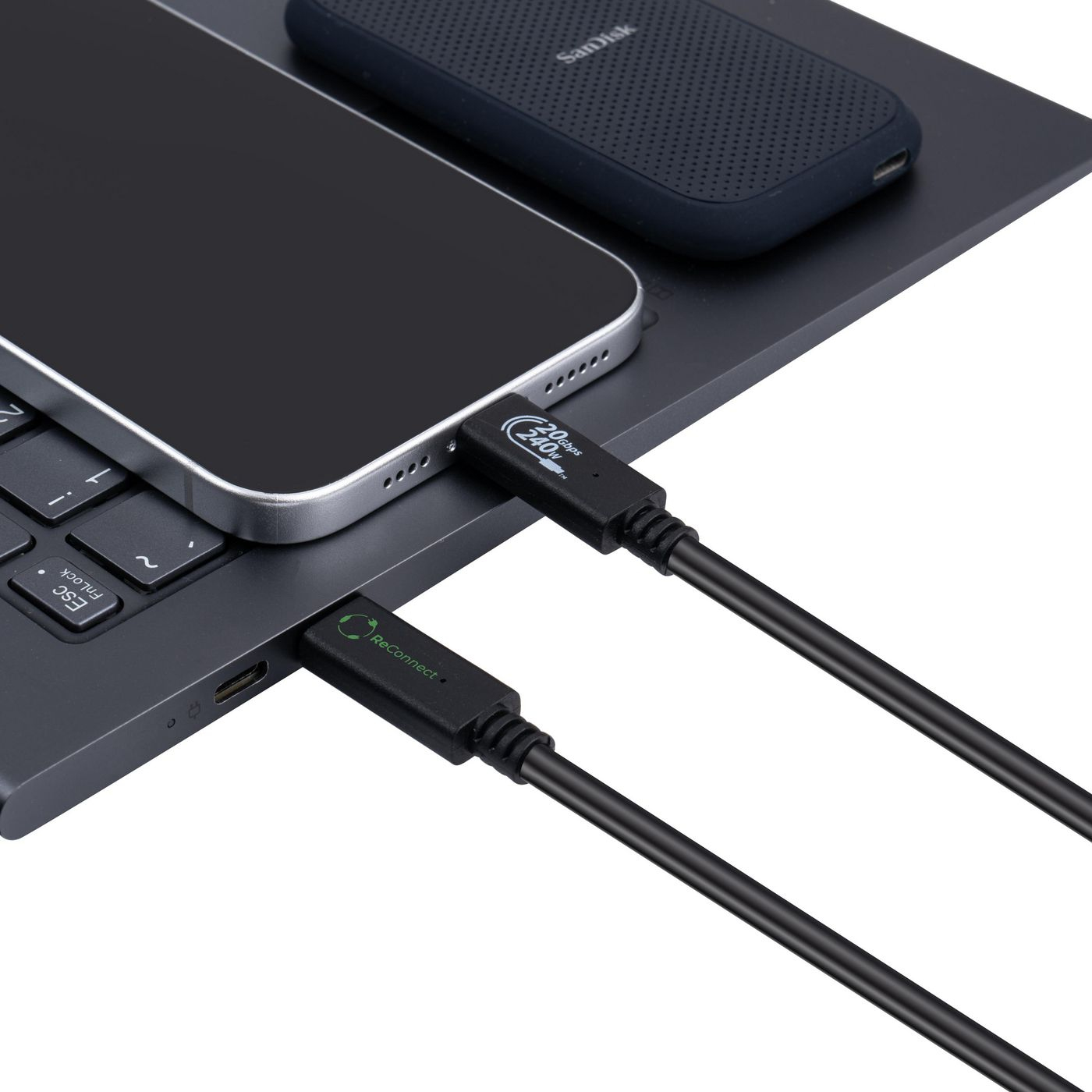 Un téléphone est connecté à un ordinateur portable via un câble USB-C noir. Un disque dur externe noir est sur la surface.