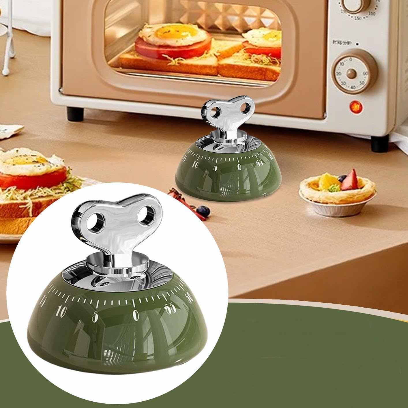 Ein grüner Küchentimer mit schlüsselartiger Oberseite steht auf einem Tisch. Ein Toaster und eine Tarte befinden sich im Hintergrund.