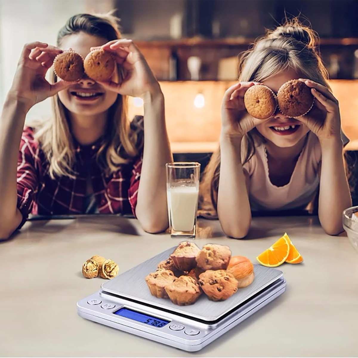 Zwei Frauen halten Muffins über ihre Augen. Eine Waage mit Muffins im Vordergrund. Orangenscheiben und ein Glas Milch sind in der Nähe.
