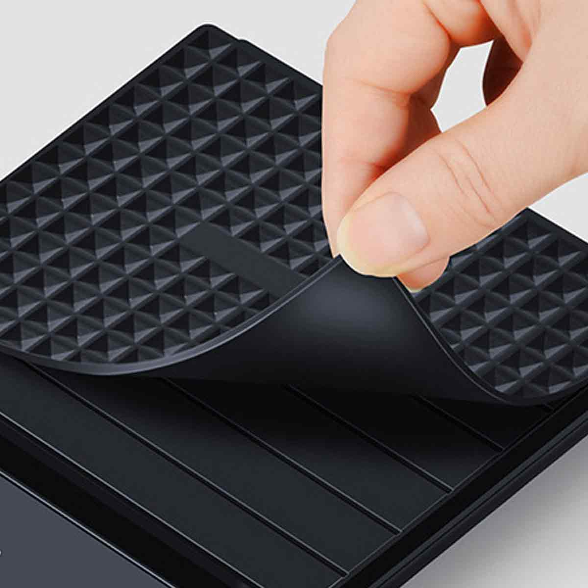 Eine Hand hebt eine schwarze Gummimatte an. Die Matte hat eine strukturierte Oberfläche und liegt über einer Schale.