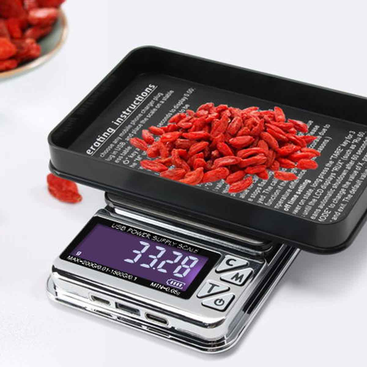 Eine Digitalwaage mit einer Schale voller roter Beeren zeigt 33,28 an. Anweisungen sind auf dem Tablett. Beeren sind verstreut.